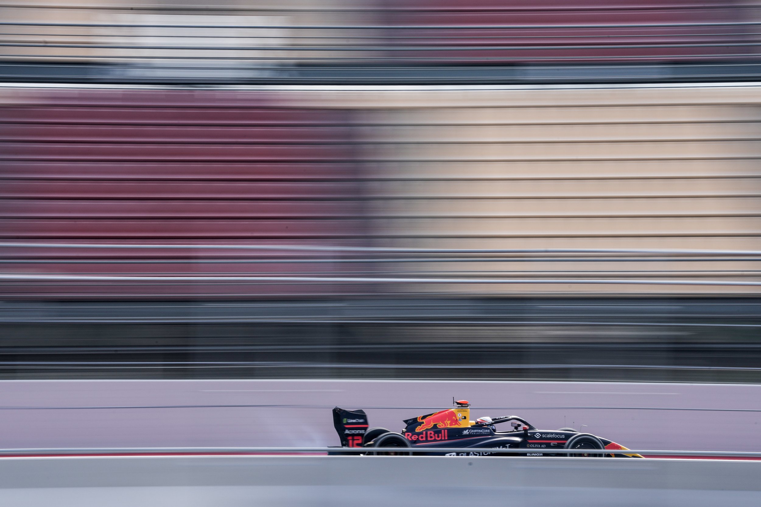 A Formula 1 race car speeding on the track with a blurred background of grandstands.