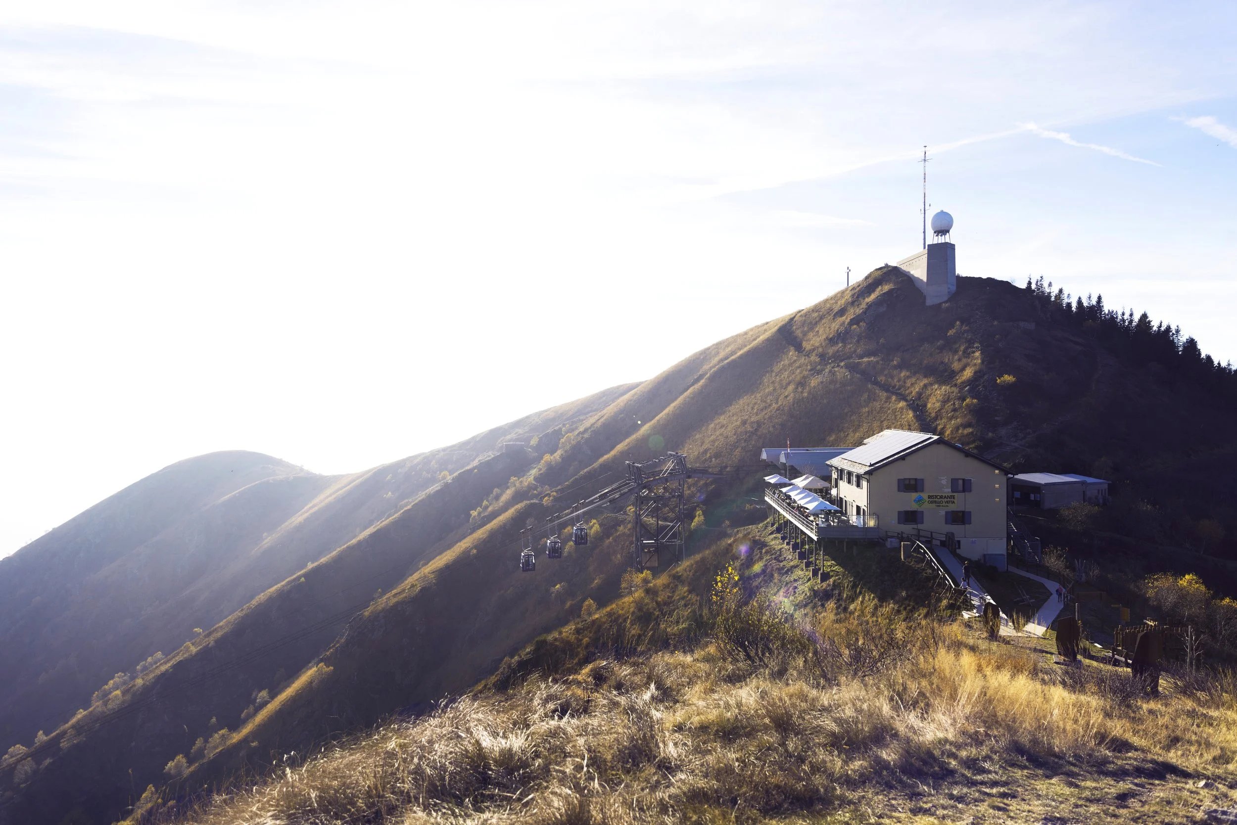 Paesaggio montano con funivia, edificio e cima con antenne
