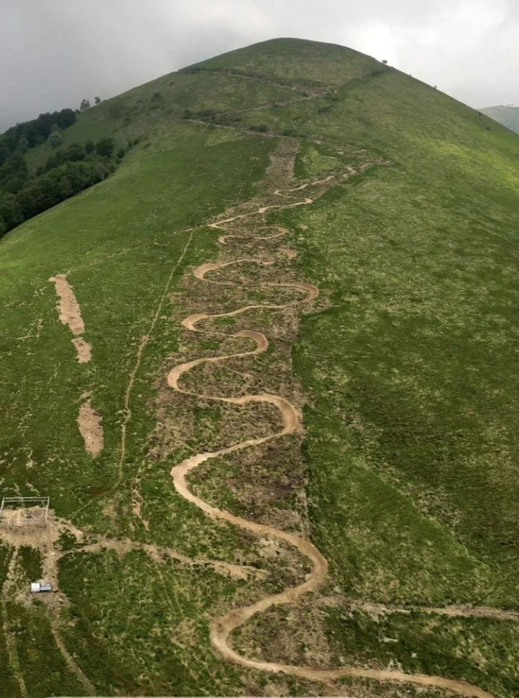 Sentiero a spirale su una collina verde con cielo nuvoloso