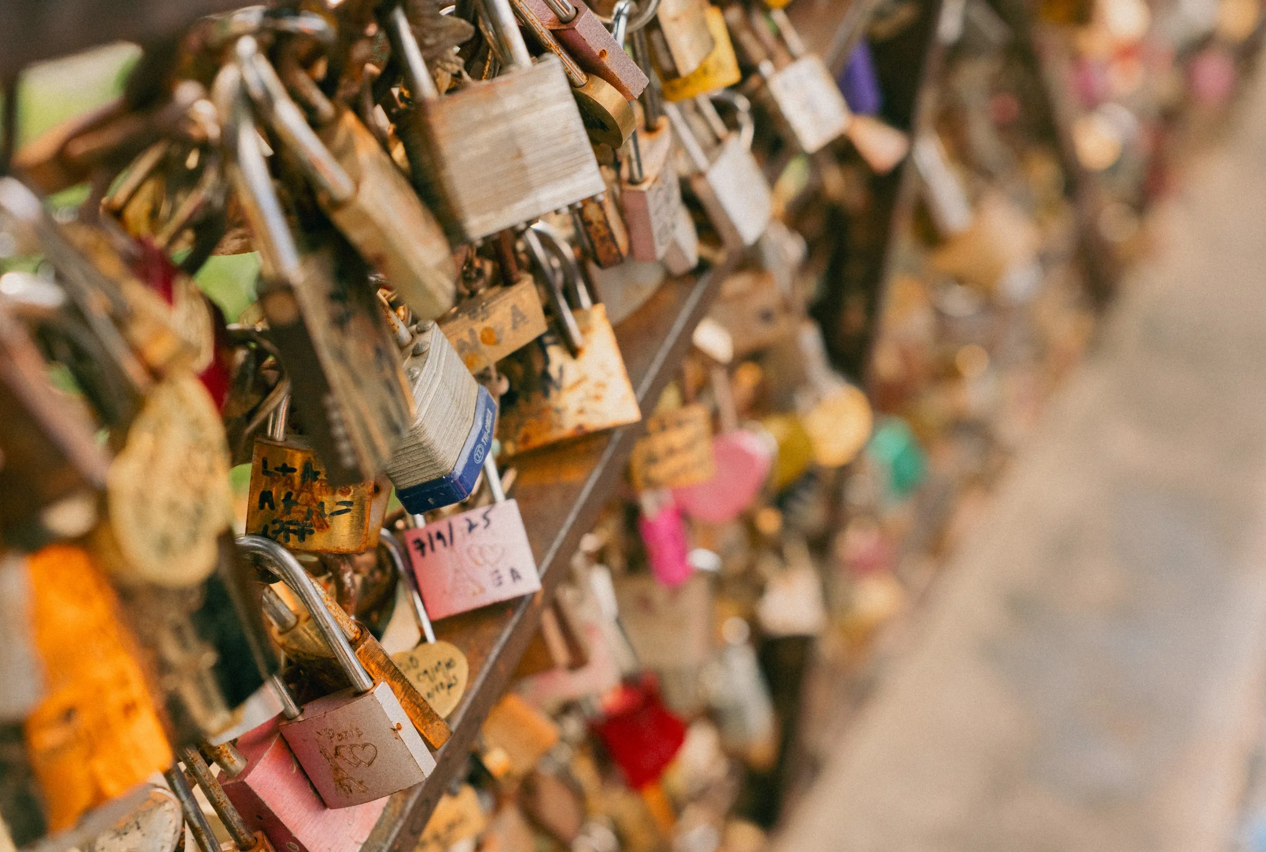 Close-up of a fence with numerous padlocks attached, symbolizing love and commitments.