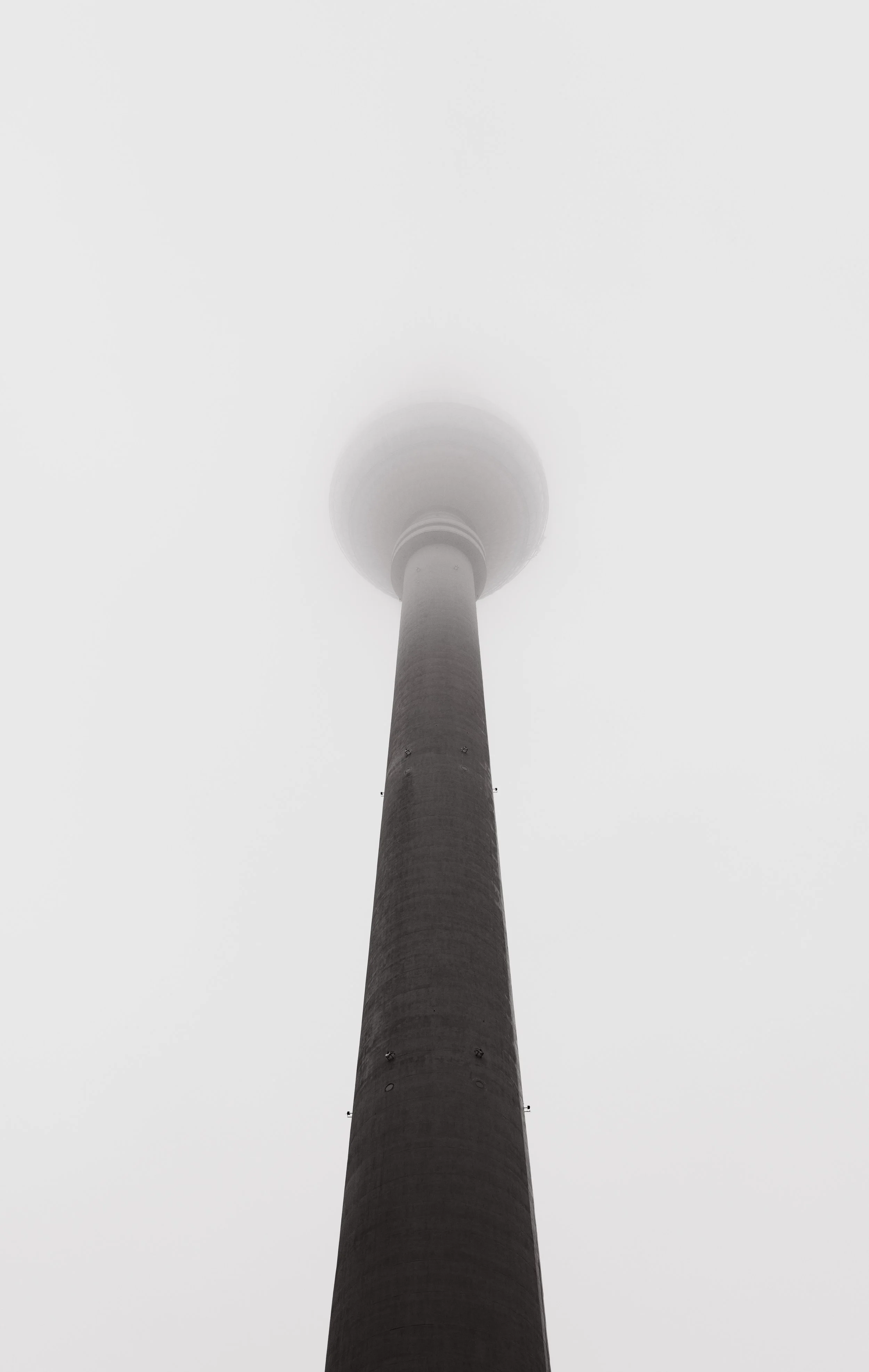 A tall tower with a spherical observation deck at the top, shrouded in dense fog