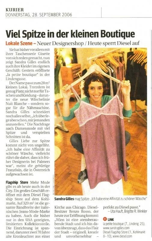 Sandra Gilles  hält ein Kleid aus ihrer Kollektion in der Hand und lächelt.