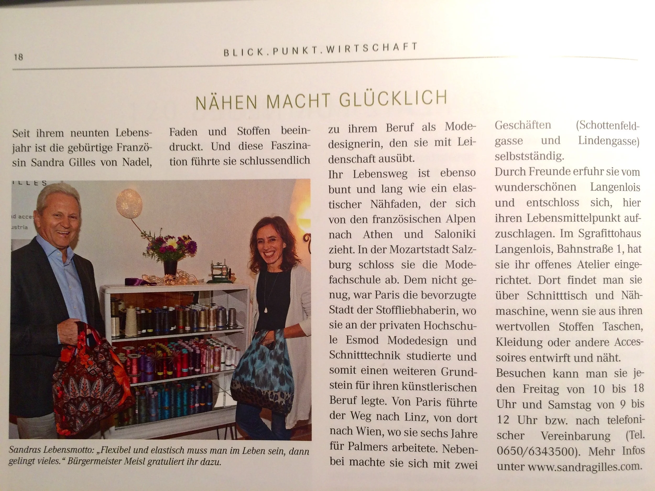 Zwei Menschen stehen neben einem Stehtisch, der mit Nähgarn und Stoffen gefüllt ist. Beide lächeln und halten Stoffbeutel in den Händen.