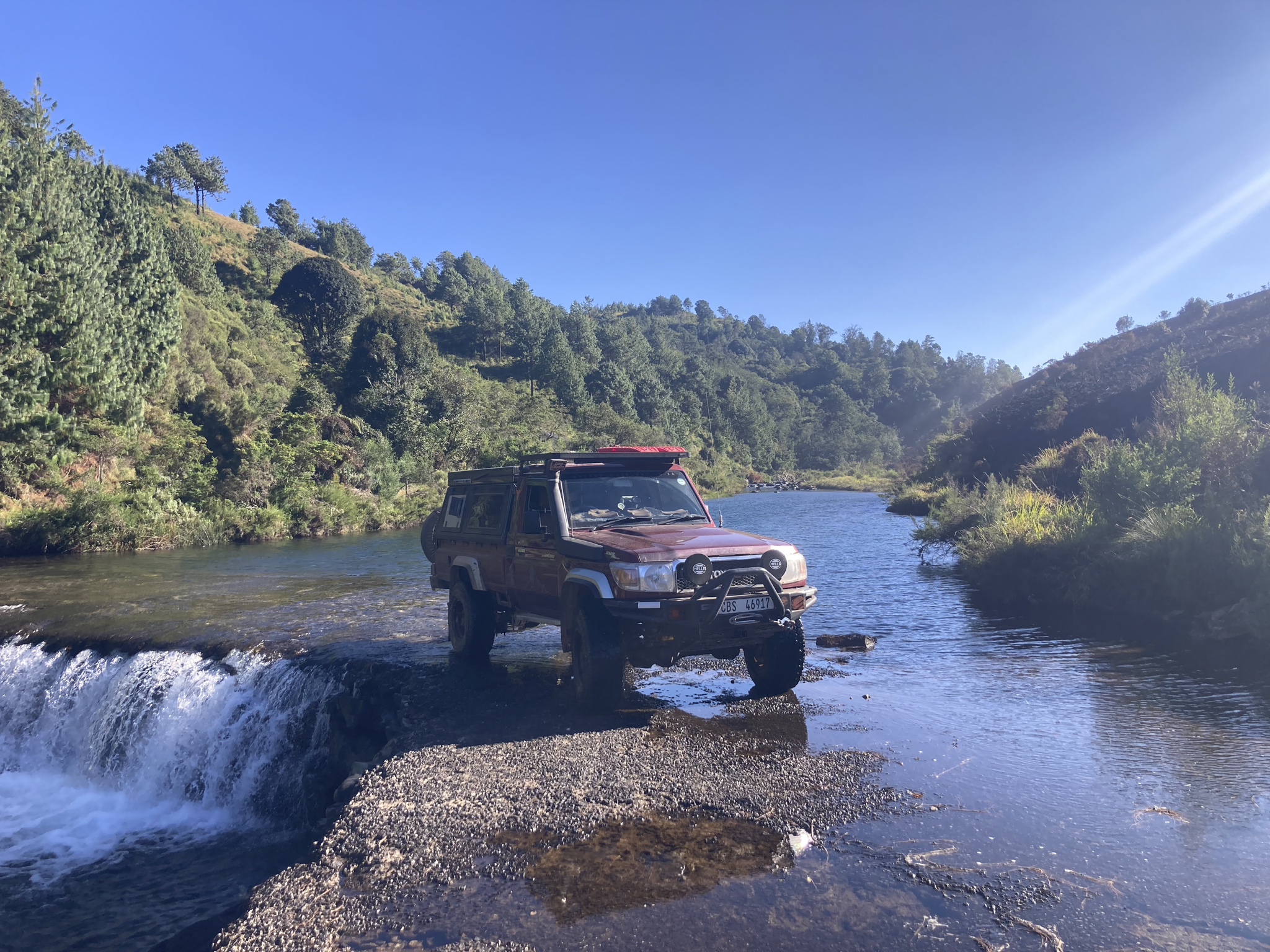 Land Cruiser 79 standing on a low level bridge over a mountain stream.