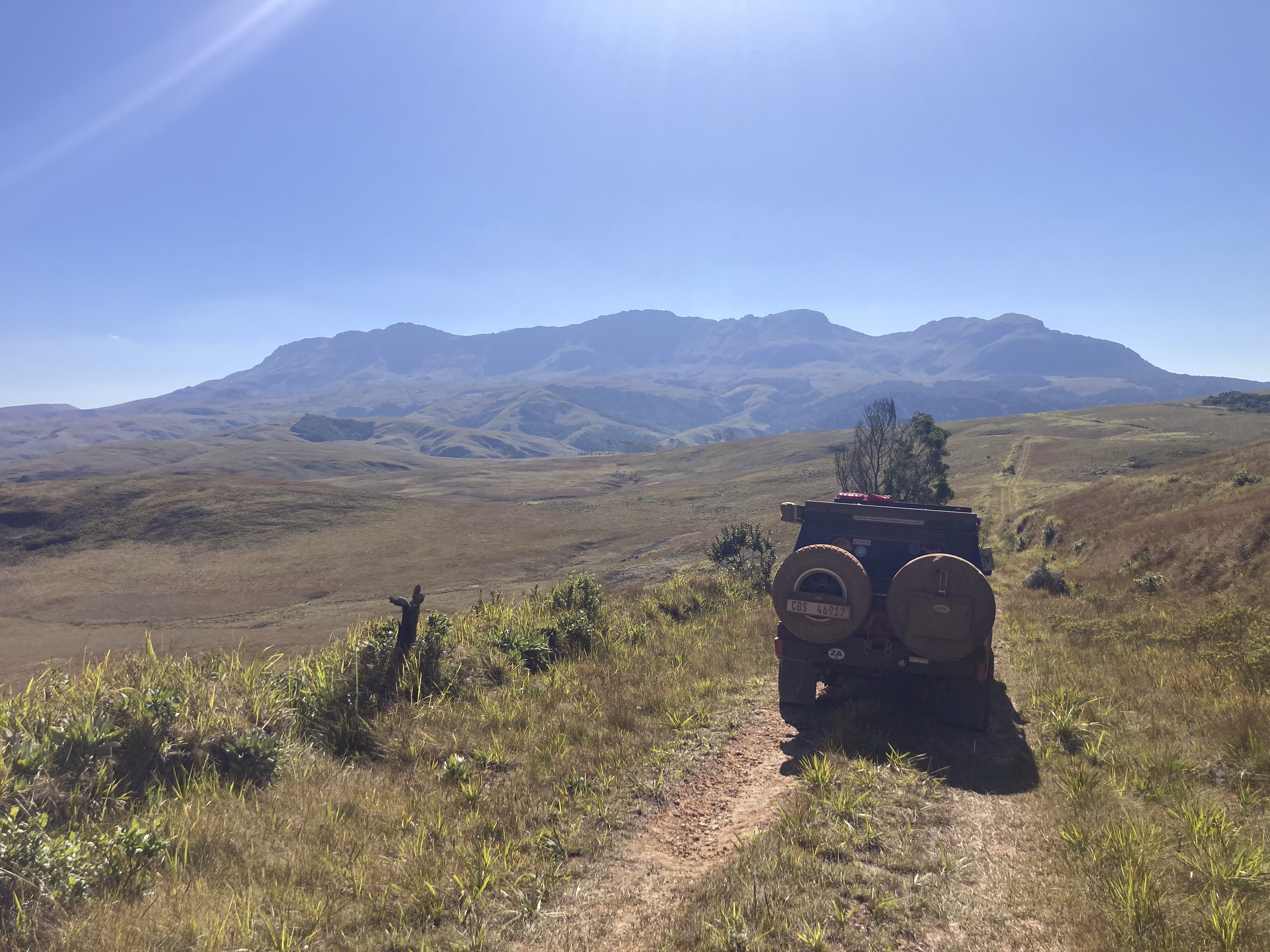 Land Cruiser 79 with green grasslands in the background and rolling mountains far out.