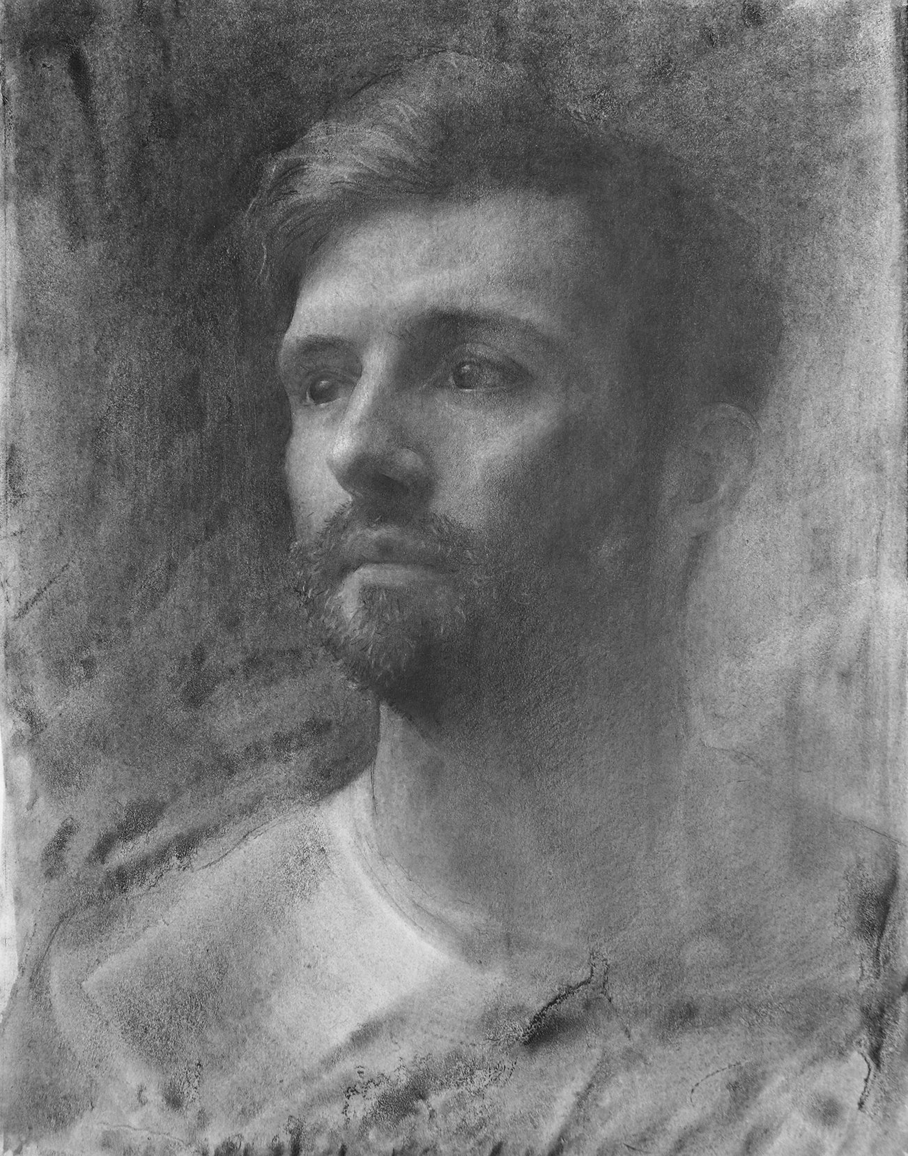 A detailed black and white pencil drawing of a man's face, with long hair and a beard, looking slightly to the side.