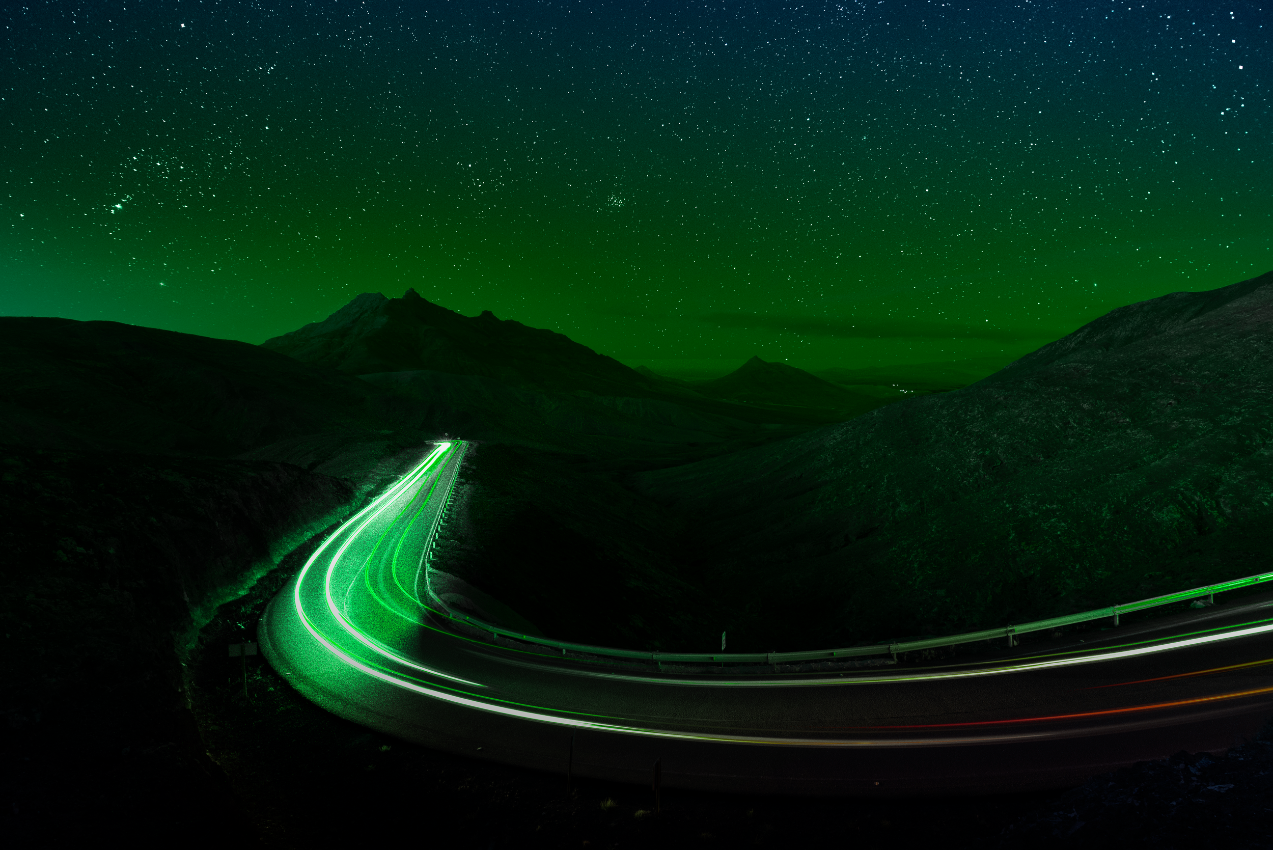 Long exposure photograph of illuminated infrastructure and moving traffic in neon green tones, representing autonomous operational intelligence, connectivity, and modern infrastructure systems.