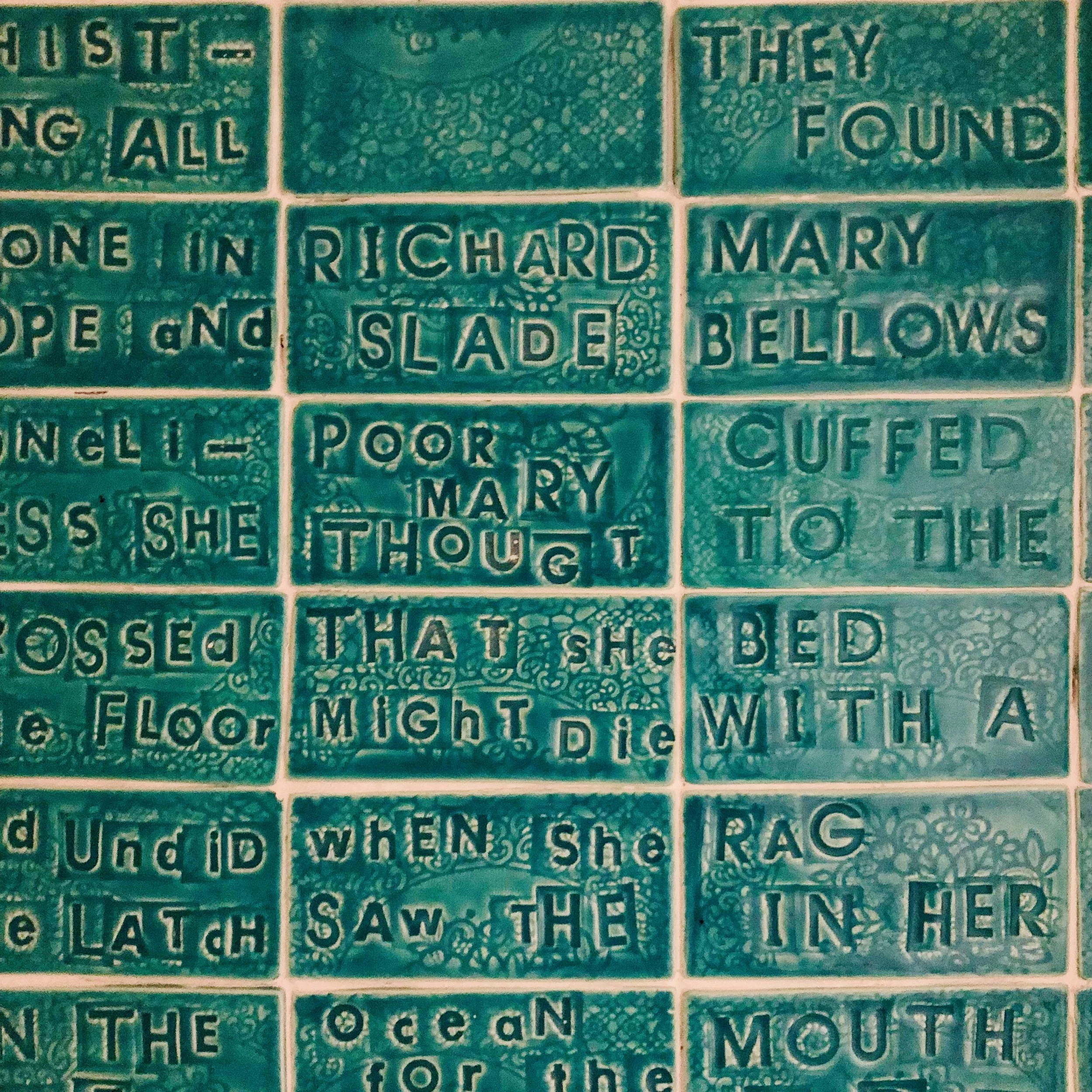 Close-up of a tiled puzzle with text in each tile, revealing parts of a story or poem about a woman named Mary.