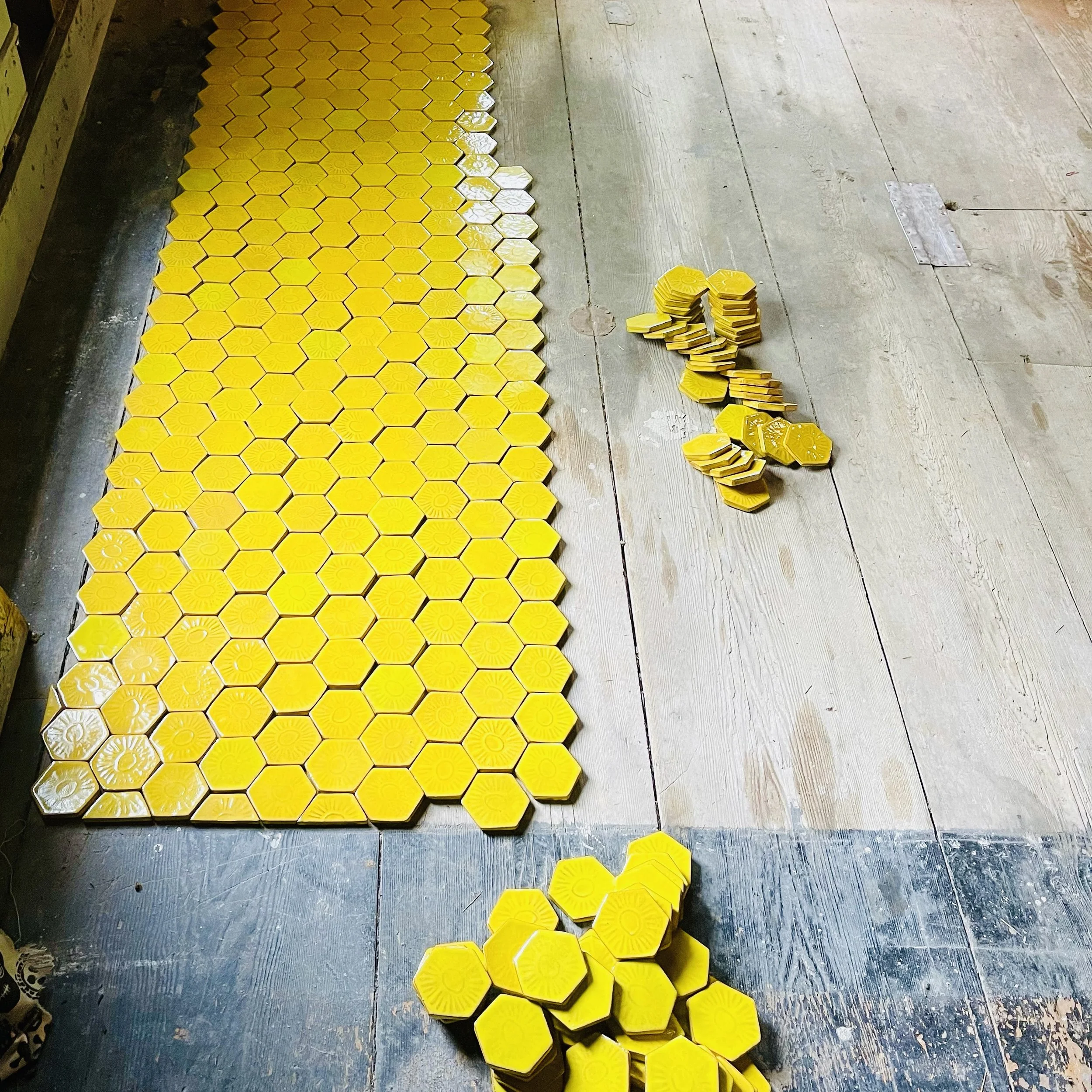 A floor with many yellow hexagonal tiles, some stacked in piles on the right side.