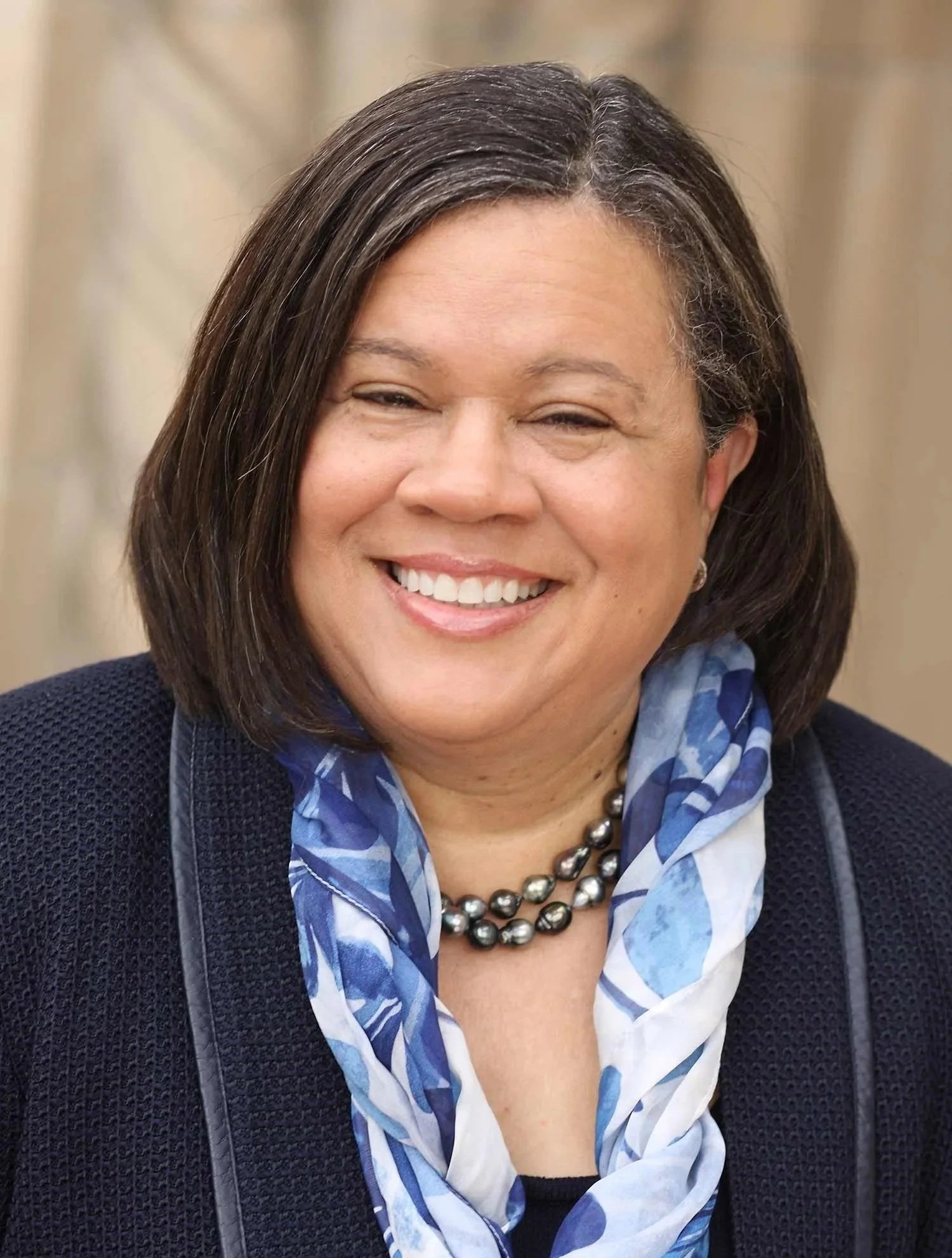 Dr Linda Oubre is a black woman with shoulder length dark hair. She is wearing a blue patterned scarf and a navy blazer