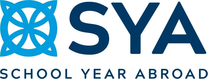 The rectangular color logo for School Year Abroad. It has floral looking circullar design to the left and the letters SYA on the right. The name school year abroad is centered smaller along the bottom.