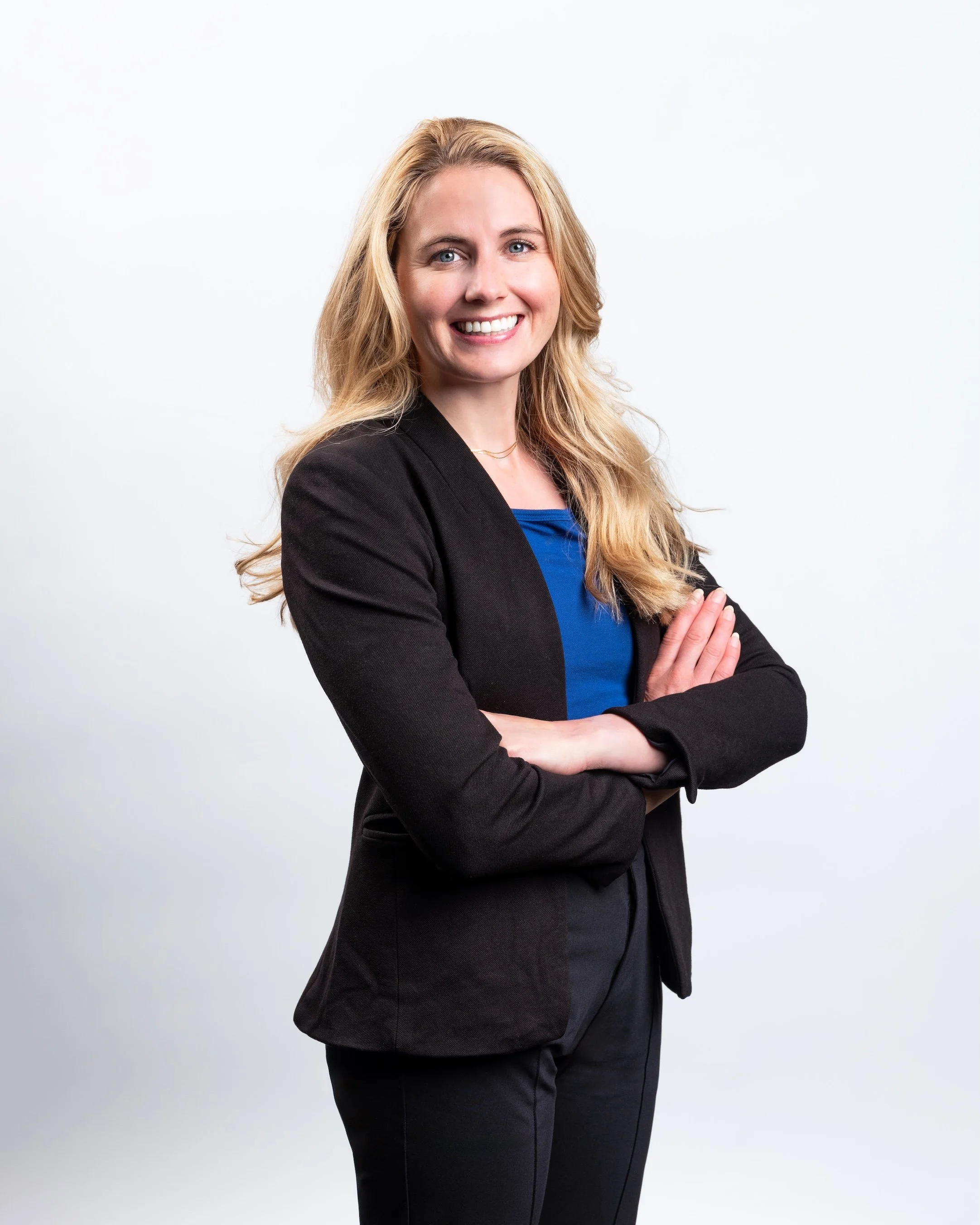 Professional Corporate Headshot by Minneapolis Photographer Jay Cupcake. Professional woman with blonde hair smiling, wearing a black blazer and blue top against a white background.