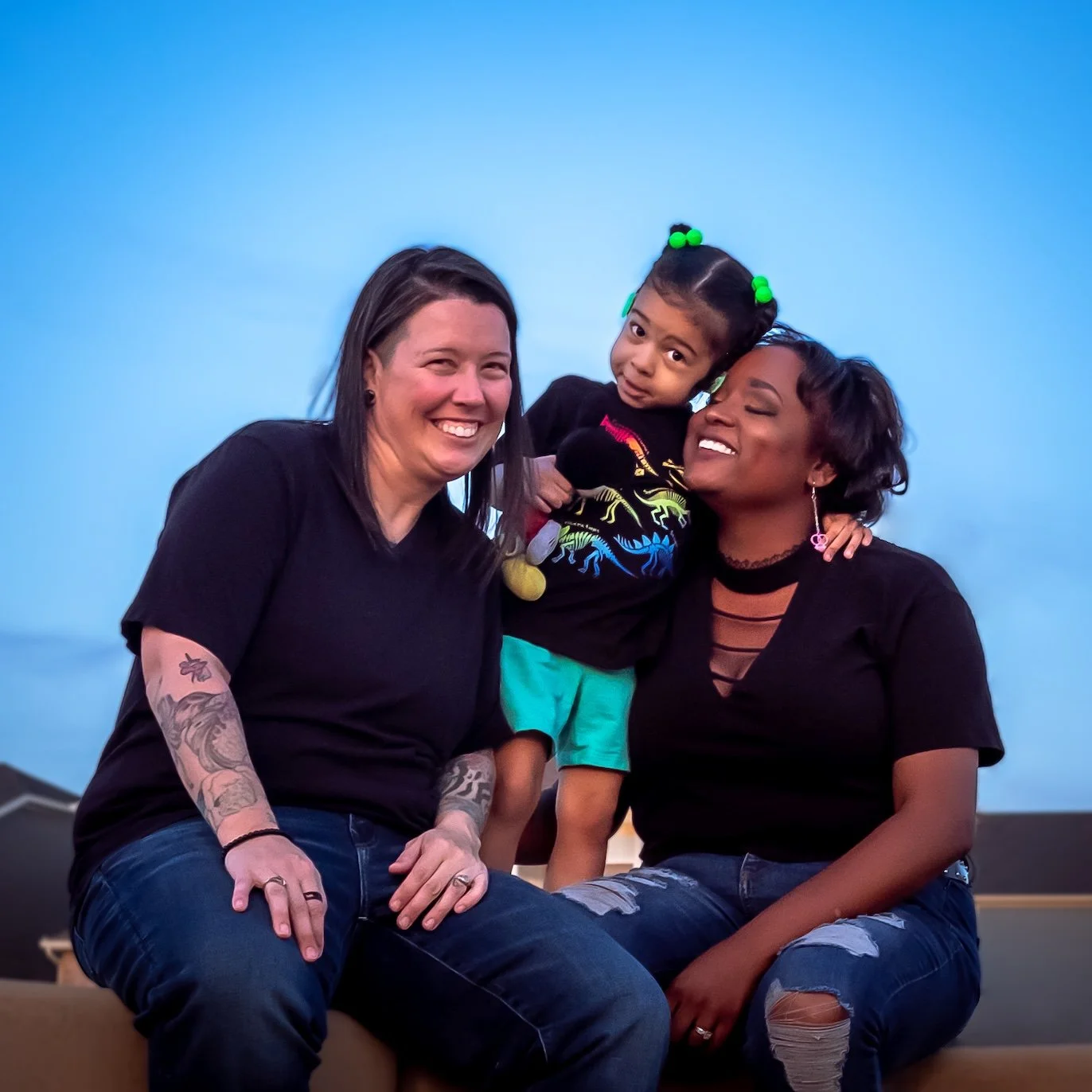 Professional Portrait Photography by Twin Cities Photographer Jay Cupcake. Three women and a young girl smiling together against a blue sky background.