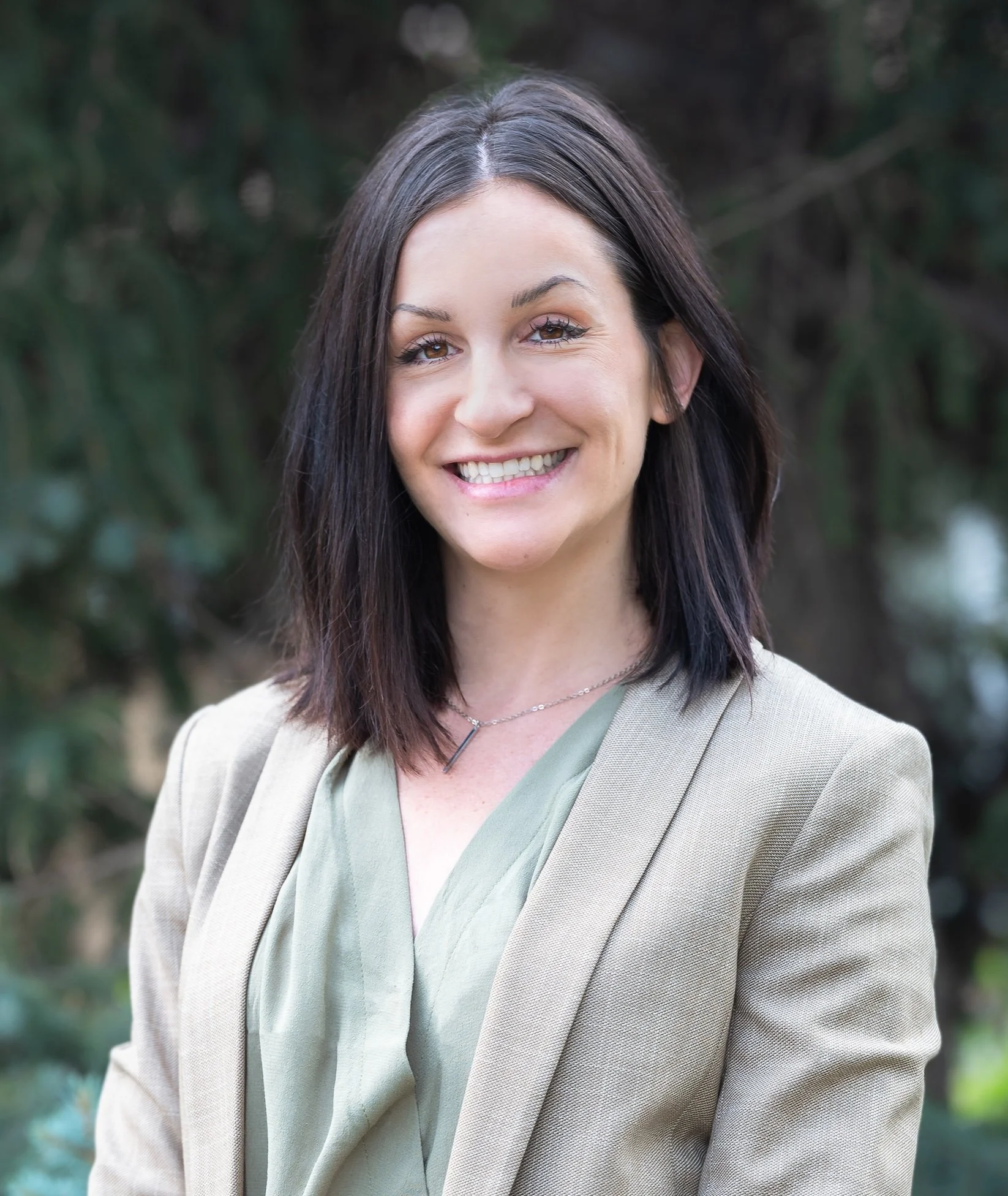 Professional Corporate Headshot by Saint Paul Photographer Jay Cupcake. A smiling woman with dark brown hair wearing a beige blazer and a light green blouse outdoors.