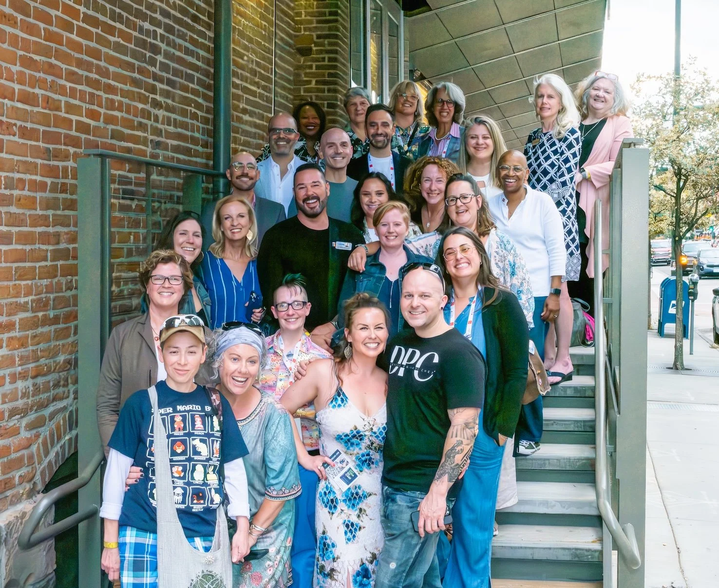 Professional Event Photography by Saint Paul Photographer Jay Cupcake. Group of smiling people gathered on outdoor stairs outside a brick building.