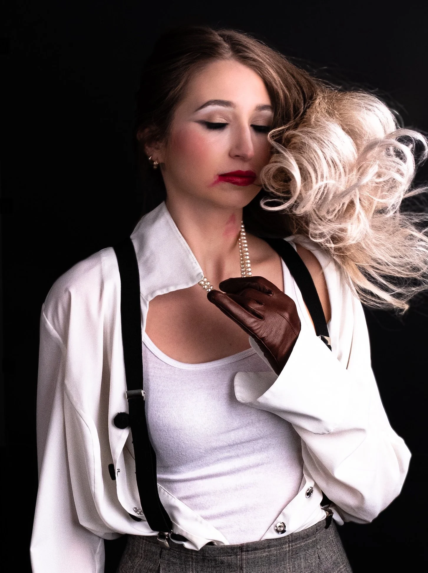 Professional Portrait Photography by Minneapolis Photographer Jay Cupcake. A woman with blonde hair and red lipstick is touching her necklace with her right hand, which is wearing a brown leather glove. She is dressed in a white shirt, white tank top