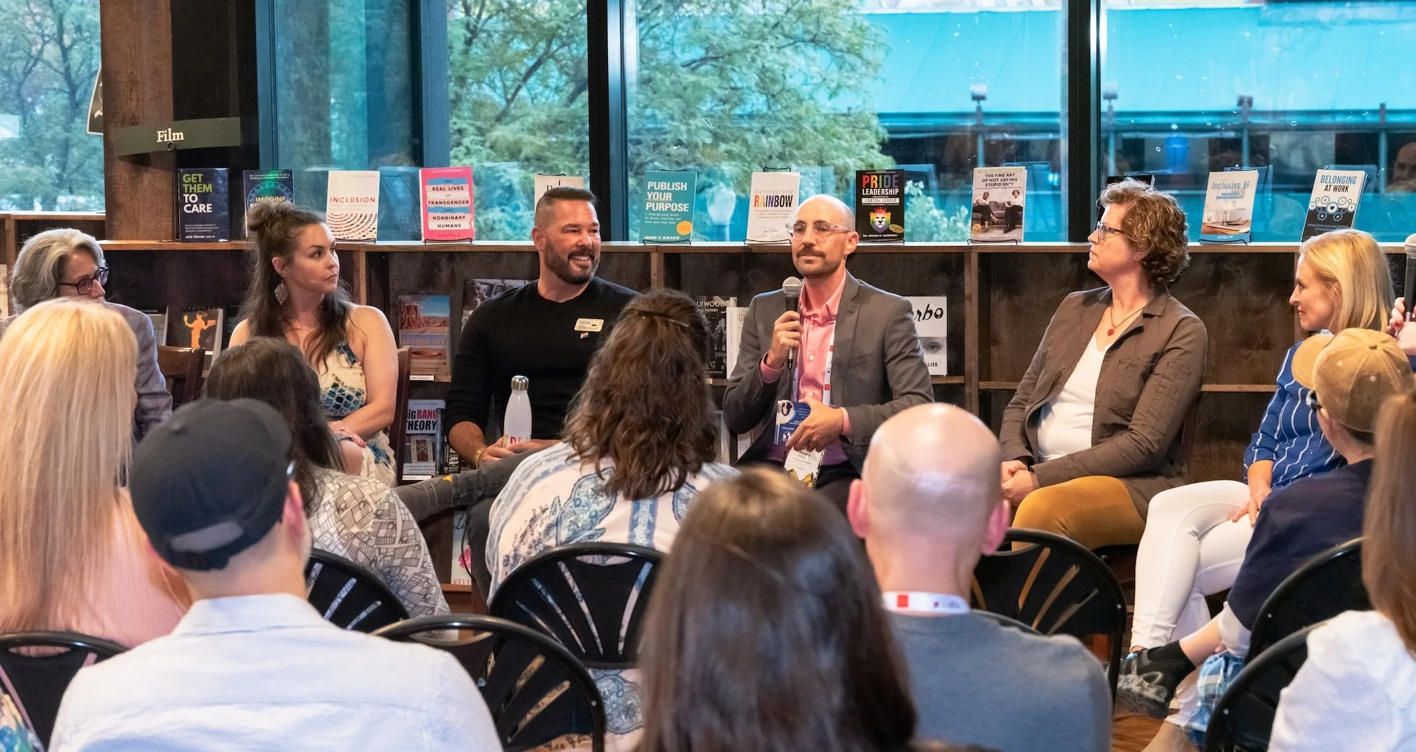 Professional Event Photography by Twin Cities Photographer Jay Cupcake. A panel of five people sitting in front of an audience at a discussion event, with books displayed on shelves behind them.