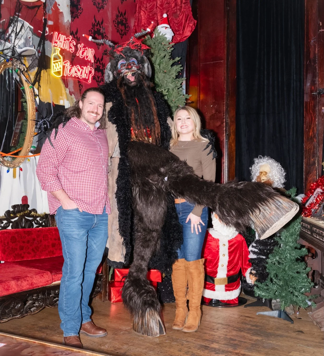 Professional Event Photography by Twin Cities Photographer Jay Cupcake. Two people posing with a large mythical creature dressed in a costume resembling a hairy, beast-like figure with long black hair, horns, and a painted face. The scene is decorate
