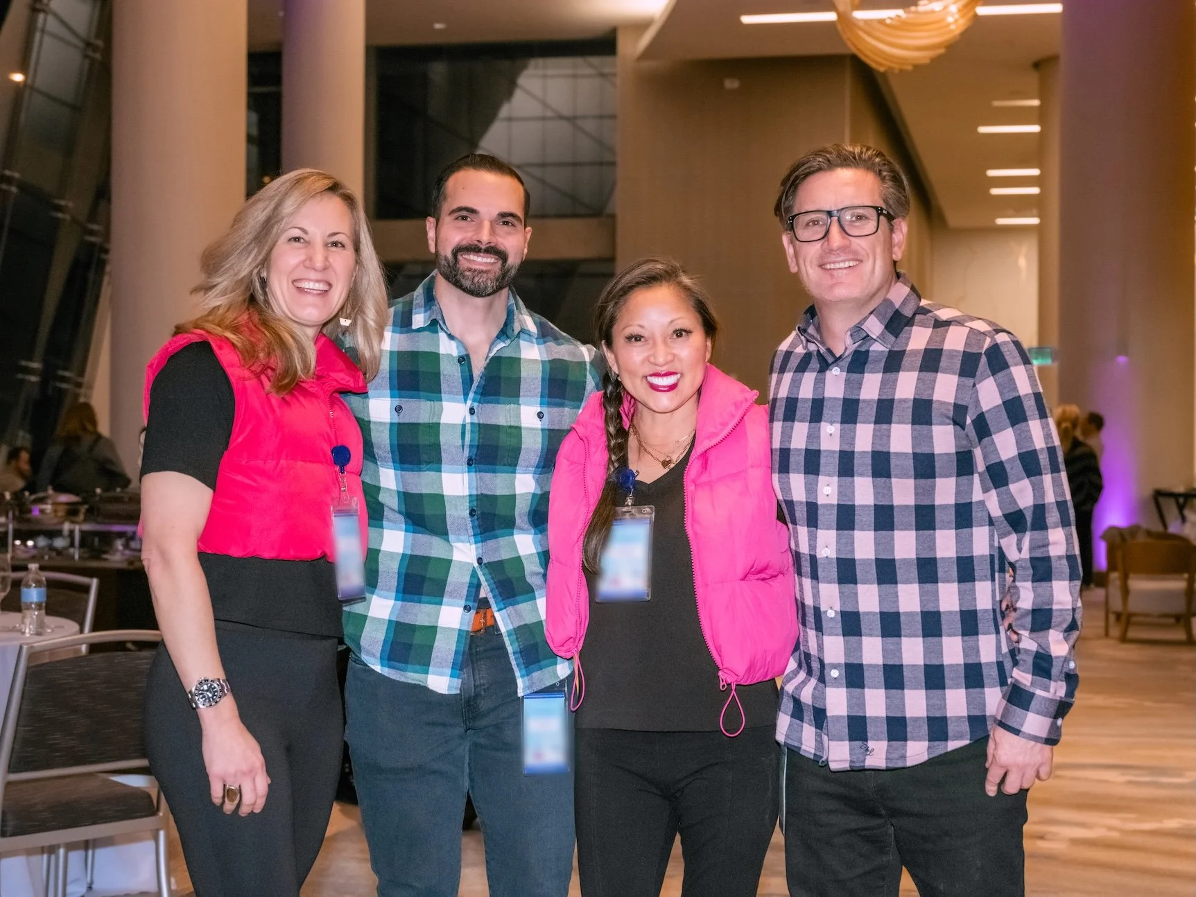 Professional Event Photography by Minneapolis Photographer Jay Cupcake. Four people smiling and posing together indoors at a conference or event, wearing casual and semi-casual clothing with event badges.