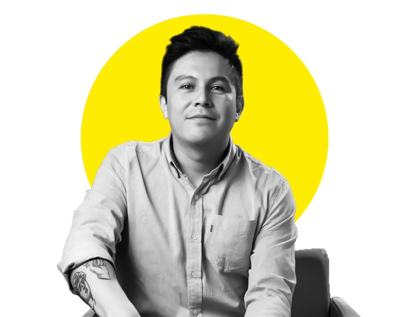 Black and white portrait of a young man with short dark hair, wearing a button-up shirt with rolled sleeves, seated in a chair with a yellow circle background.