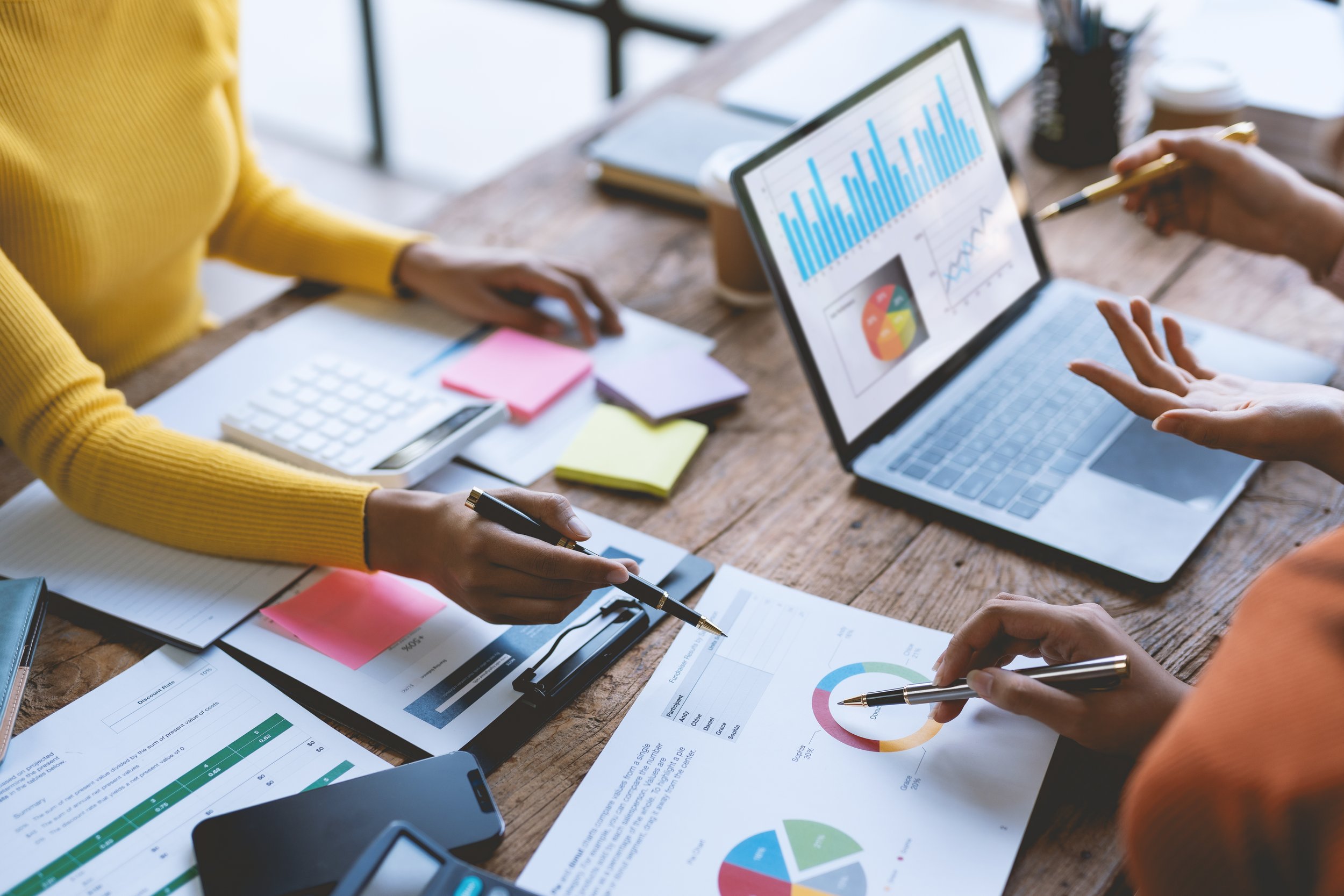 Business meeting with two people discussing charts and graphs on papers and laptop in a conference room.