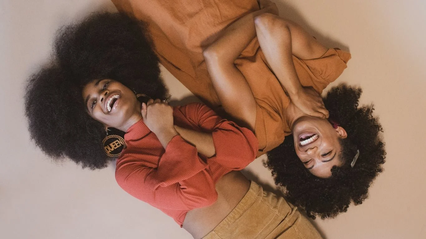 Two women lying next to each other in opposite directions, both smiling