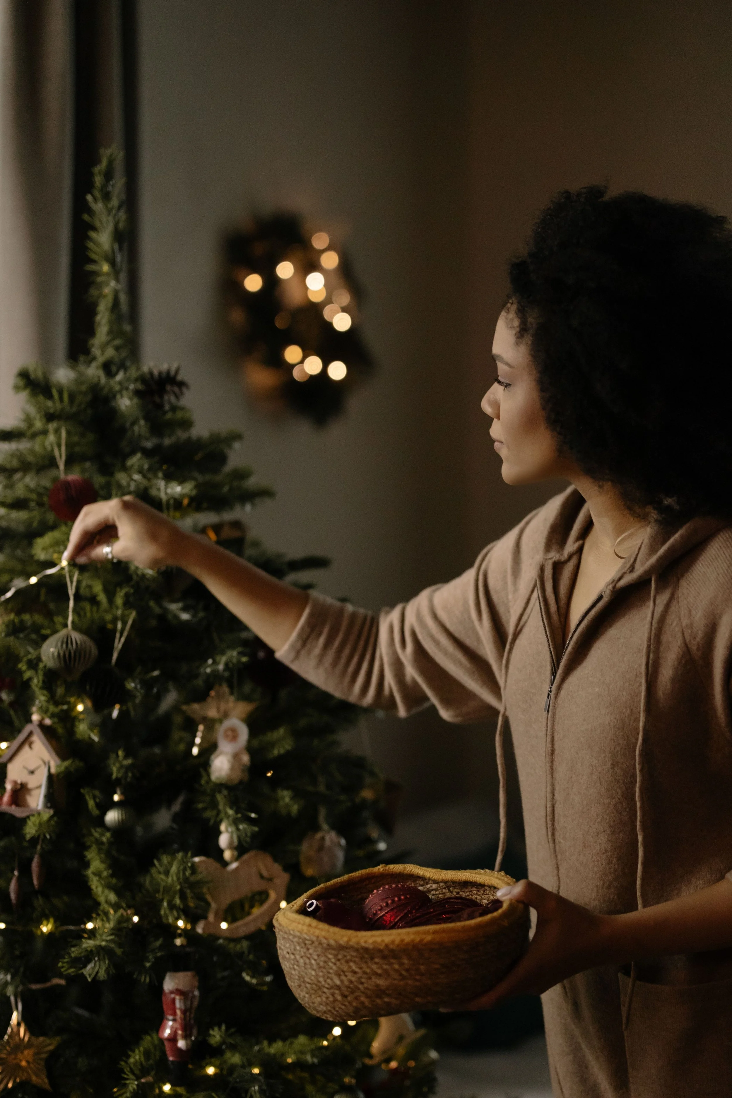 A Black woman in a quiet, grounded moment during the holiday season, representing the practice of self-preservation and maintaining healing progress when re-entering complicated family systems.