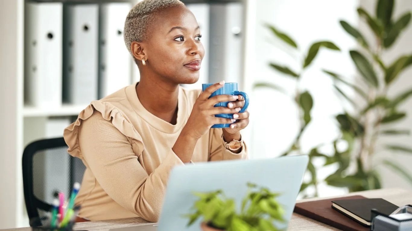 Woman sitting at a desk holding a mug