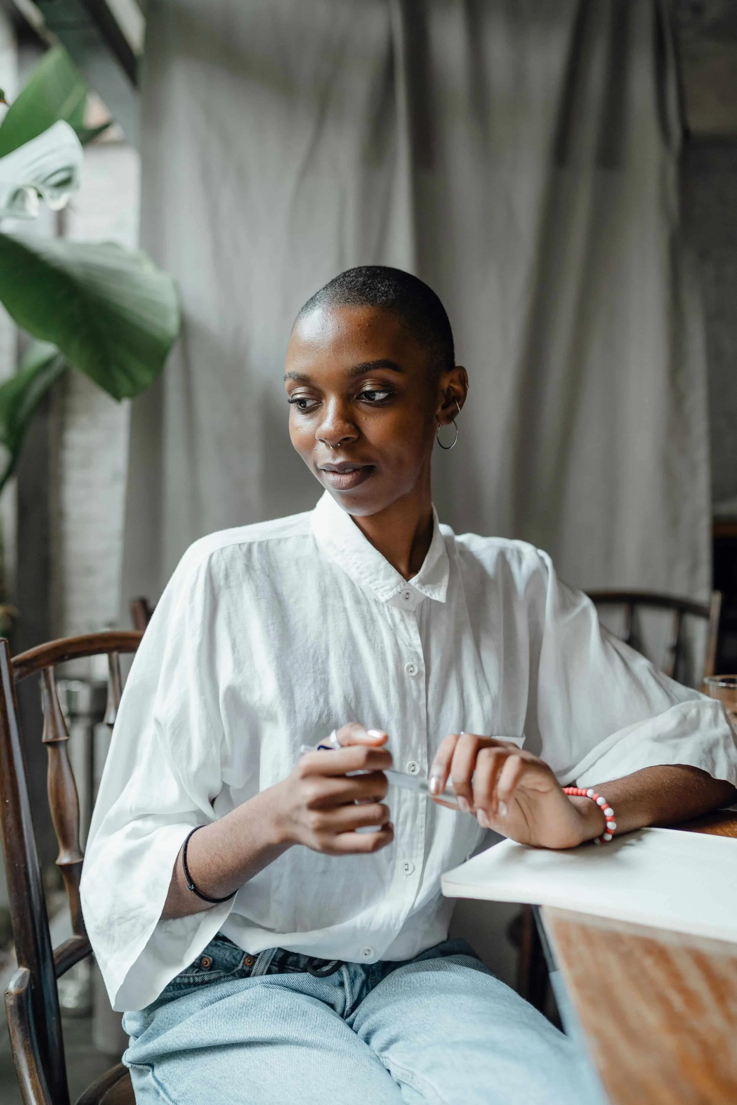 Woman sitting at a table with a pen and notebook gazing into the distance