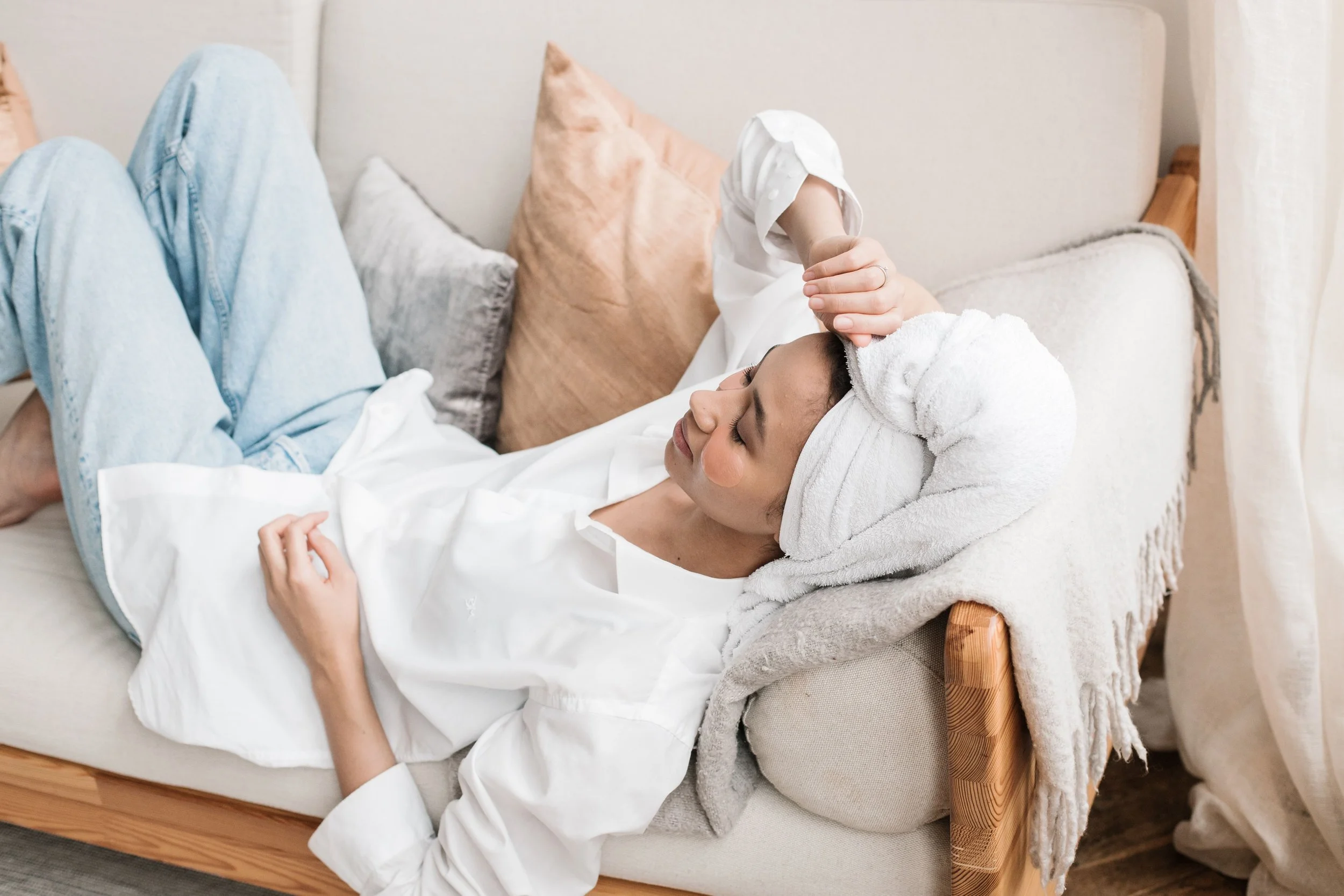 A Black woman lying down with her eyes closed in a quiet moment, representing the exhaustion that high-functioning anxiety produces and the need for nervous system rest rather than just physical rest.