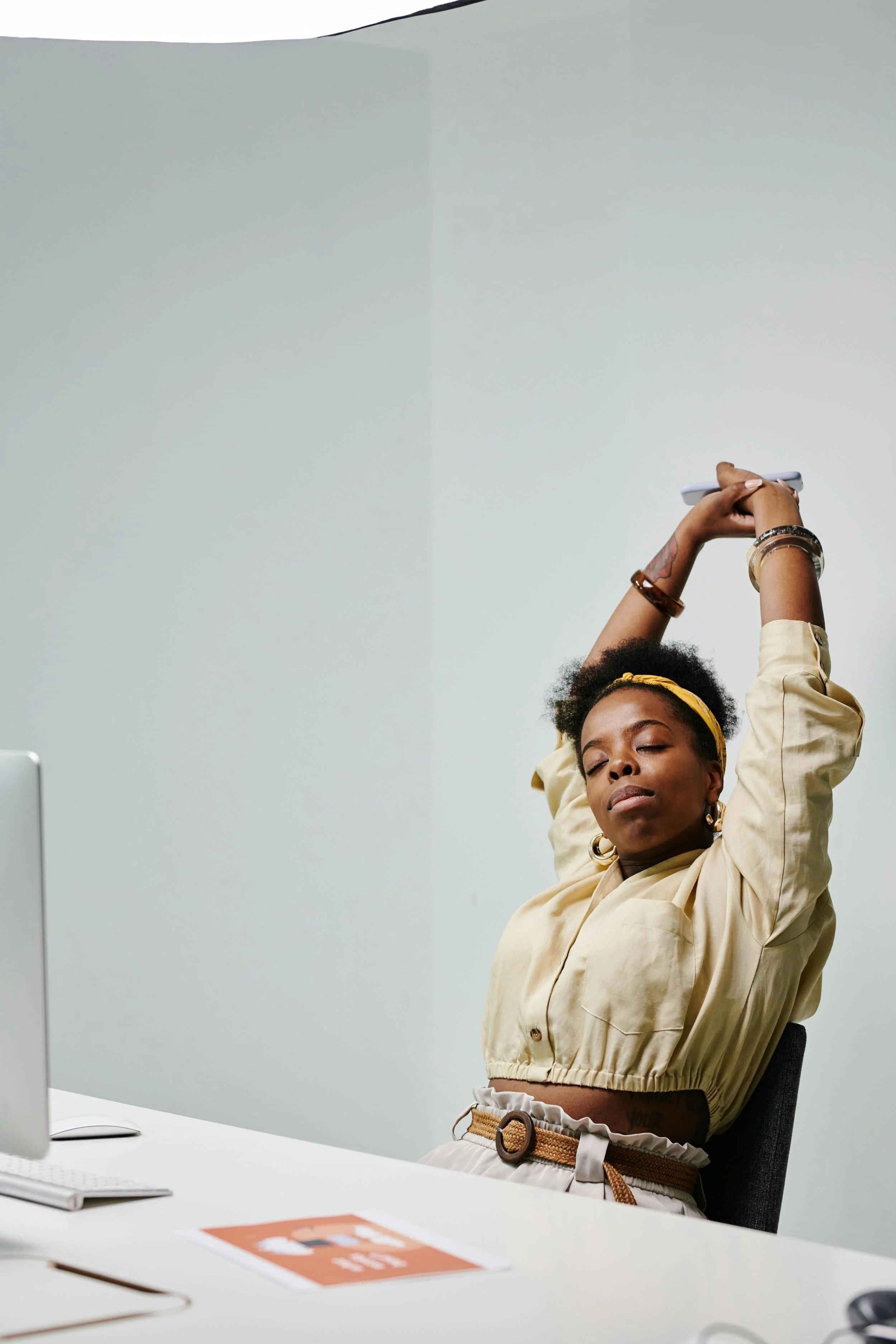 Woman sitting at a desk stretching her arms above her head