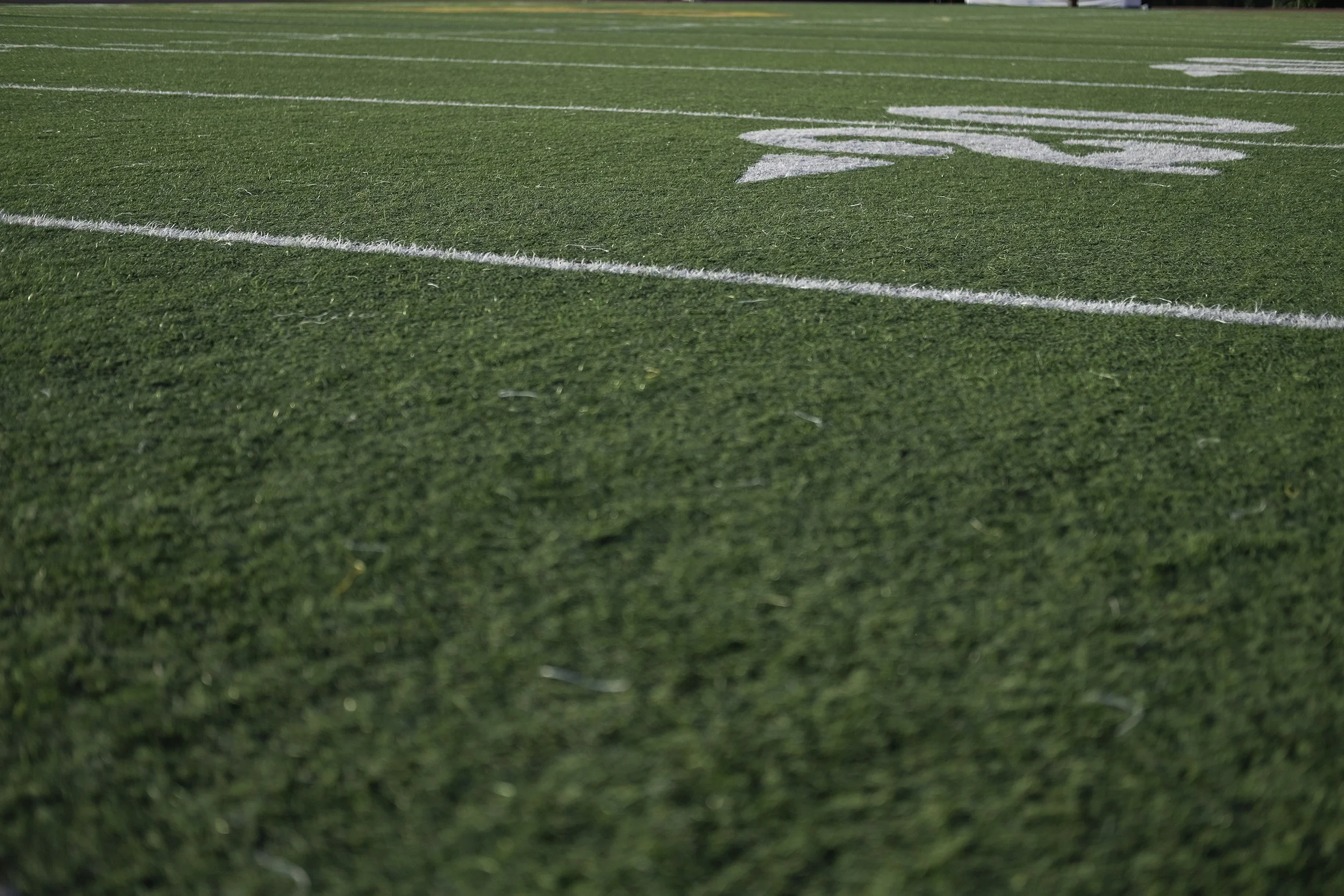 A football field with green turf and white yard lines and markings.