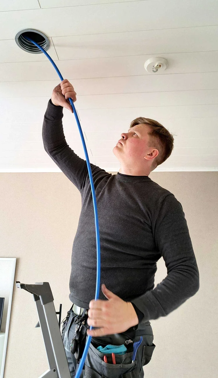 Ilmateknikko Antti Lepikko puhdistaa ilmanvaihtoventtiiliä käyttäen sinistä ilmastointiharjaa.