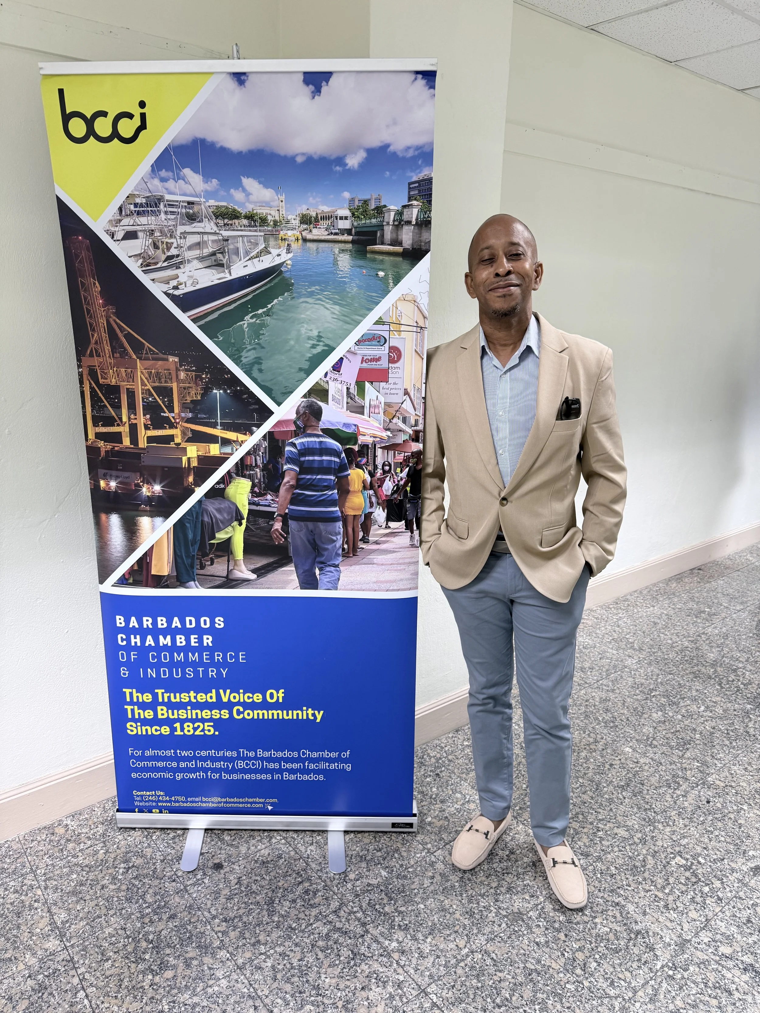 Sheldon S. Browne beside Barbados Chamber of Commerce and Industry event display