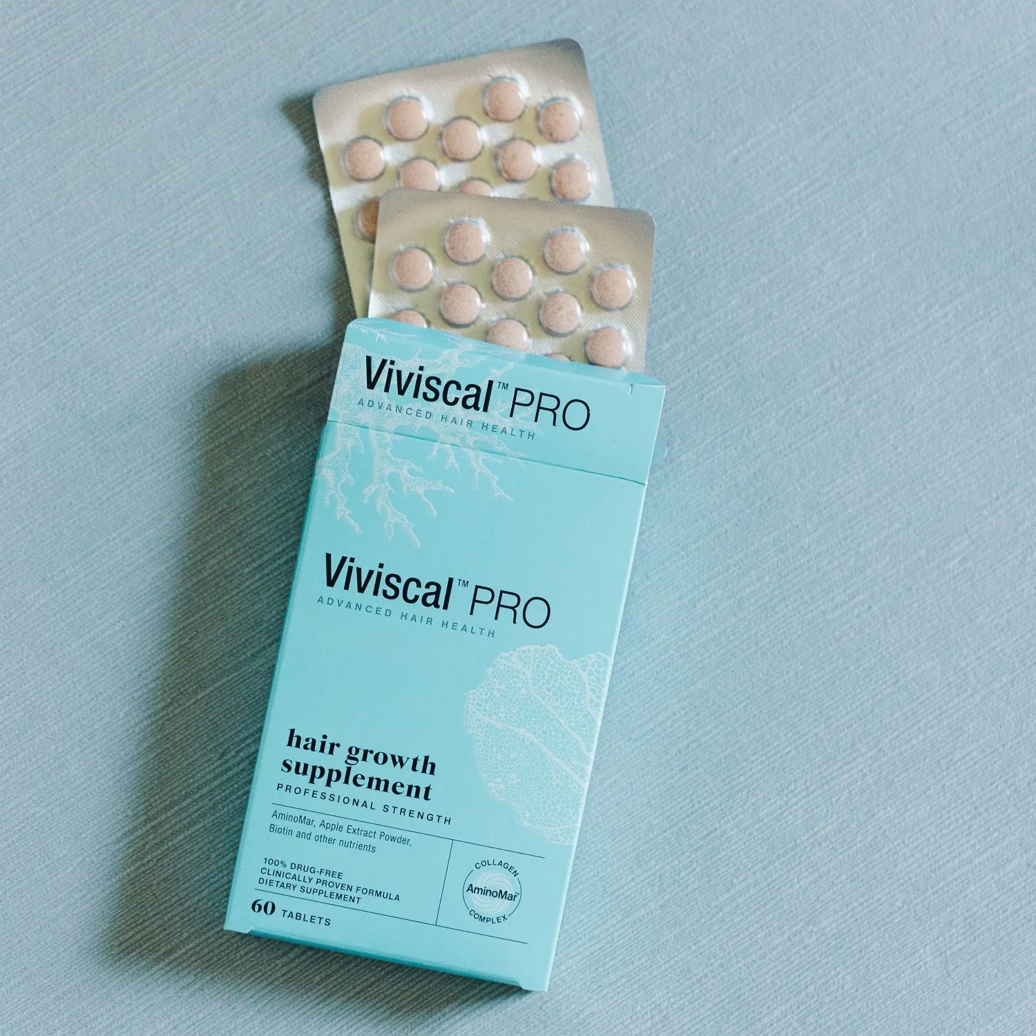 A box of Viviscal Pro hair growth supplements next to two blister packs of tablets on a light-colored surface.