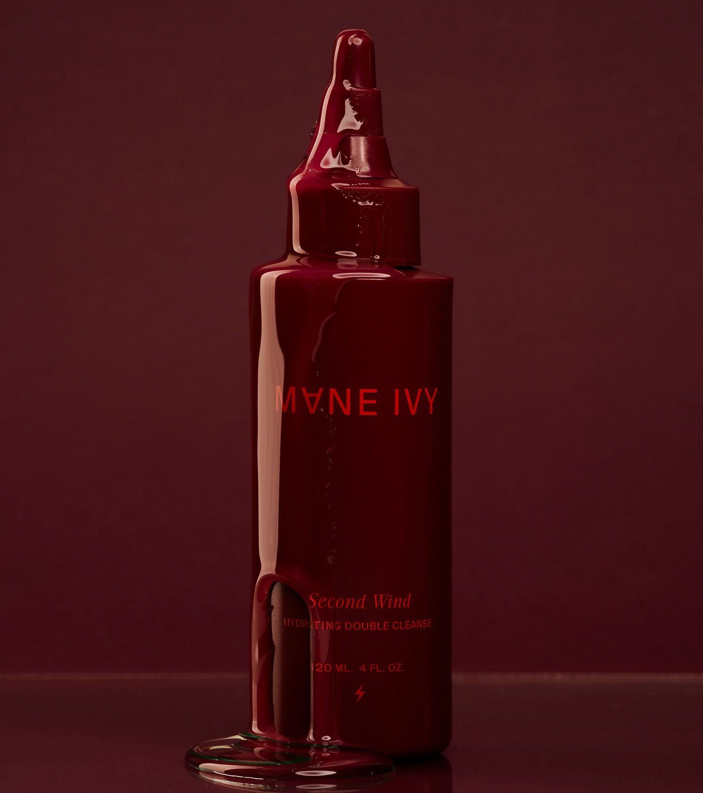 A red skincare product bottle with a drip of liquid running down its side, set against a matching dark red background.
