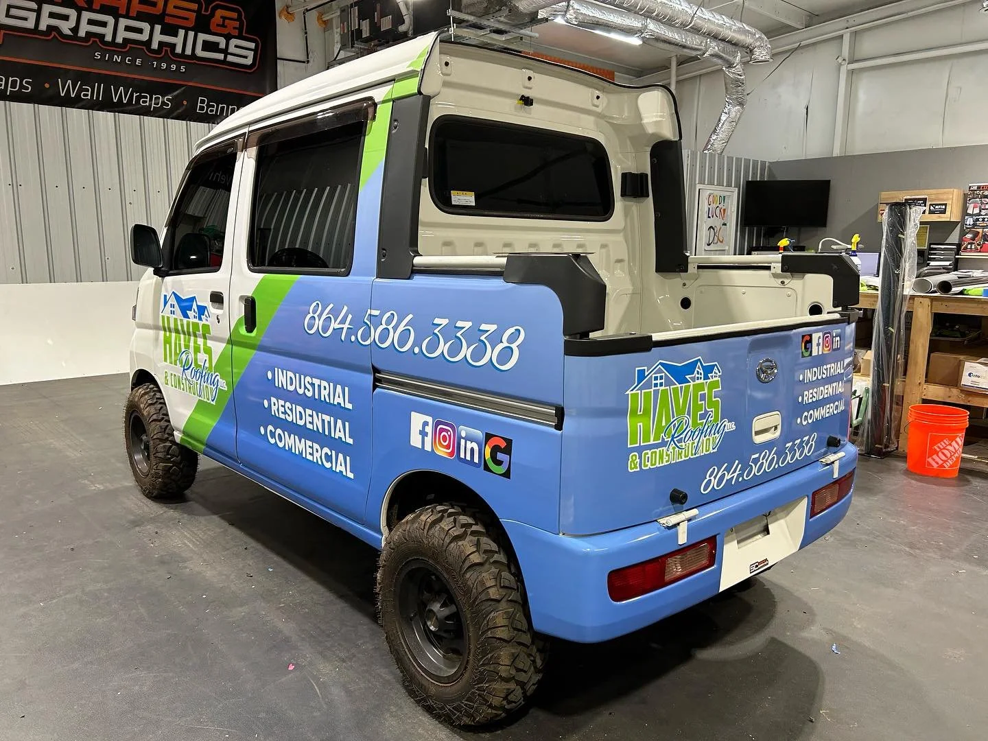 Custom logo and contact information for Hayes Roofing & Construction on a small utility vehicle, parked indoors.