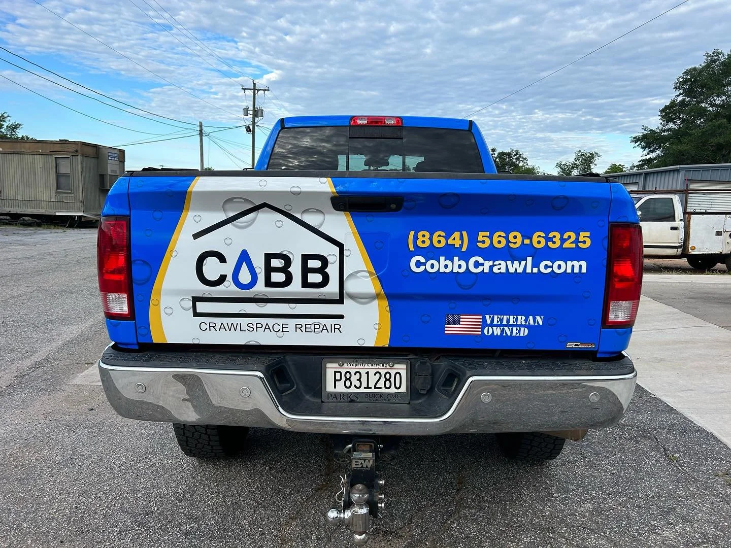 Back of a blue pickup truck with a Cobb Crawlspace Repair advertisement, phone number, website, and veteran-owned logo.