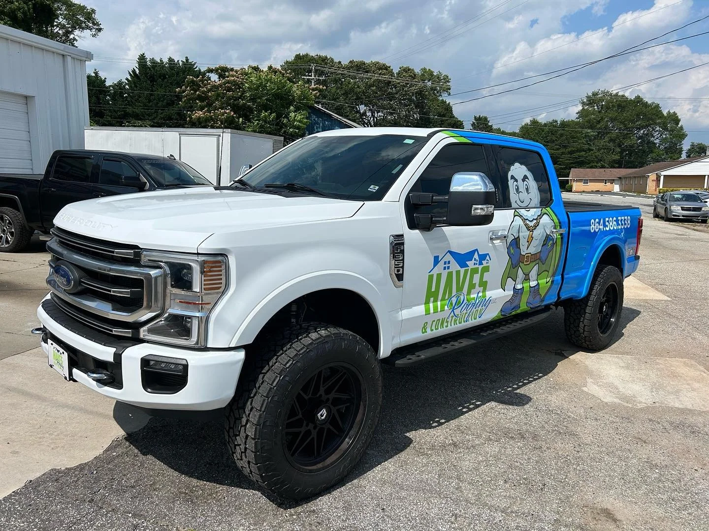 White Ford pickup truck with a colorful wrap advertising Haves Plumbing & Construction, featuring a cartoon superhero character, house logo, contact number, and company branding.