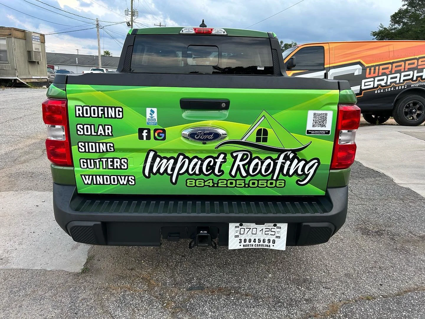 Green pickup truck with impact roofing advertisement on its tailgate, listing services like roofing, solar, siding, gutters, and windows, along with a phone number, social media icons, and a logo of a house with a roof.