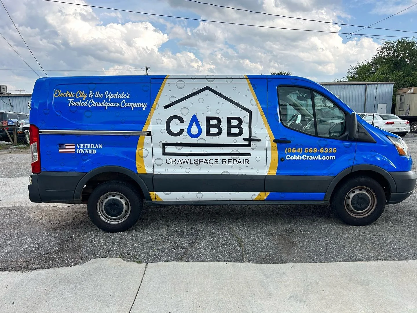 Blue work van for COBB crawlspace repair with company logo, contact information, and slogan, parked on a street during daytime.
