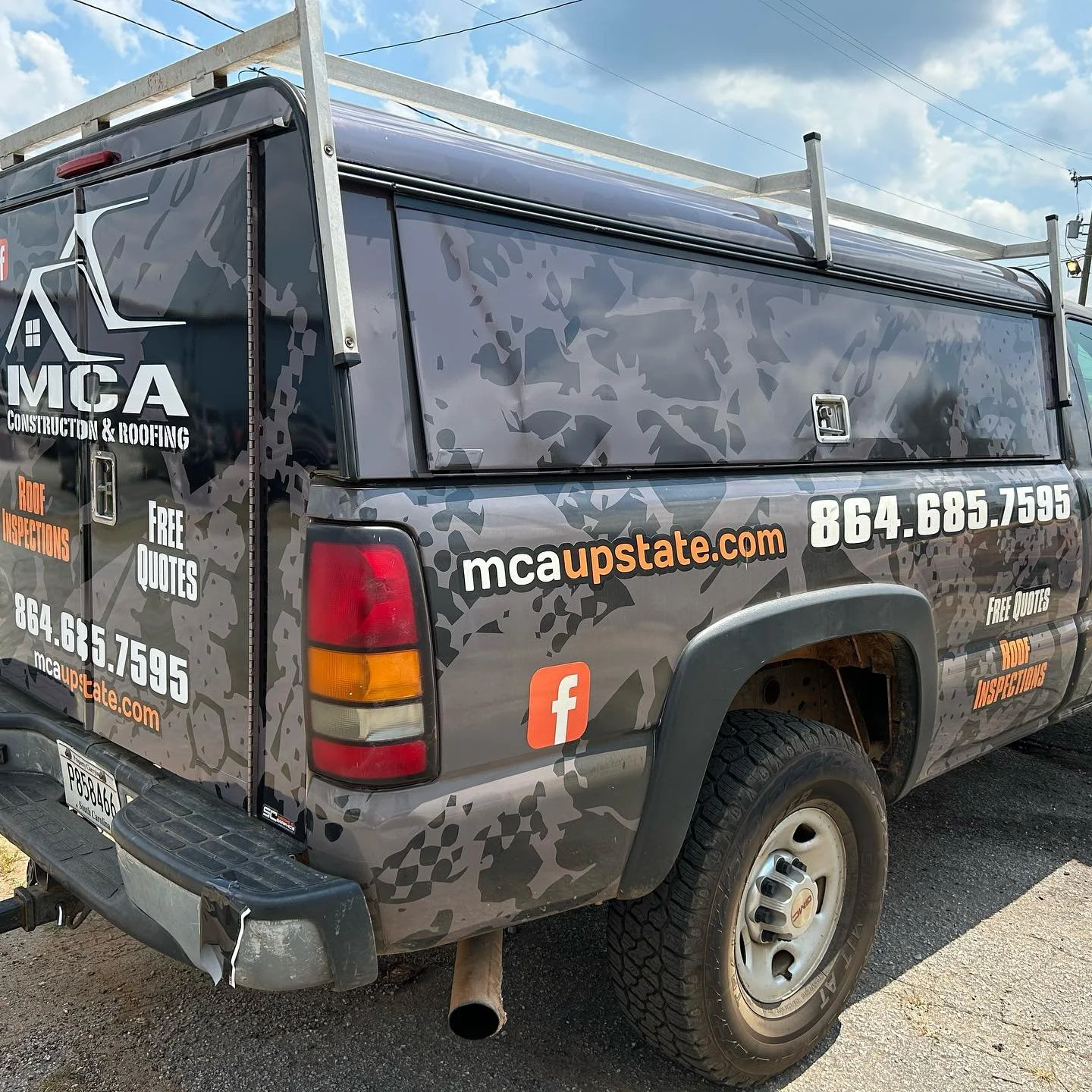A truck advertising MCA Construction & Roofing with the website mcaupstate.com, phone number 864.685.7595, and a Facebook logo.