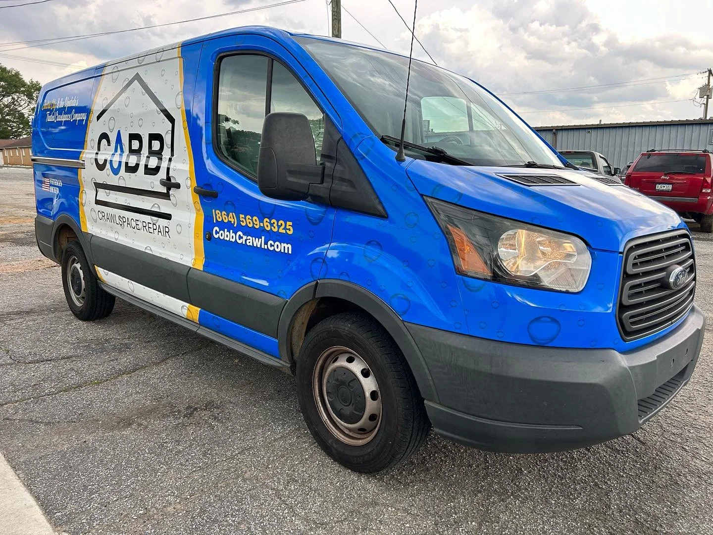 Blue service van with Cobb Crawl logo and contact information parked in a lot.