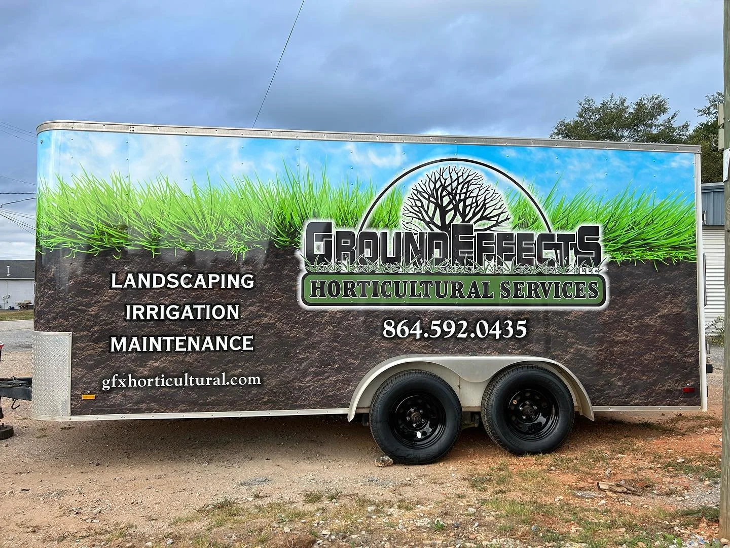 A trailer advertising Ground Effects LLC, a landscaping and horticultural services business. The trailer's design features a grassy top, a soil background, a logo with a tree, and contact information.