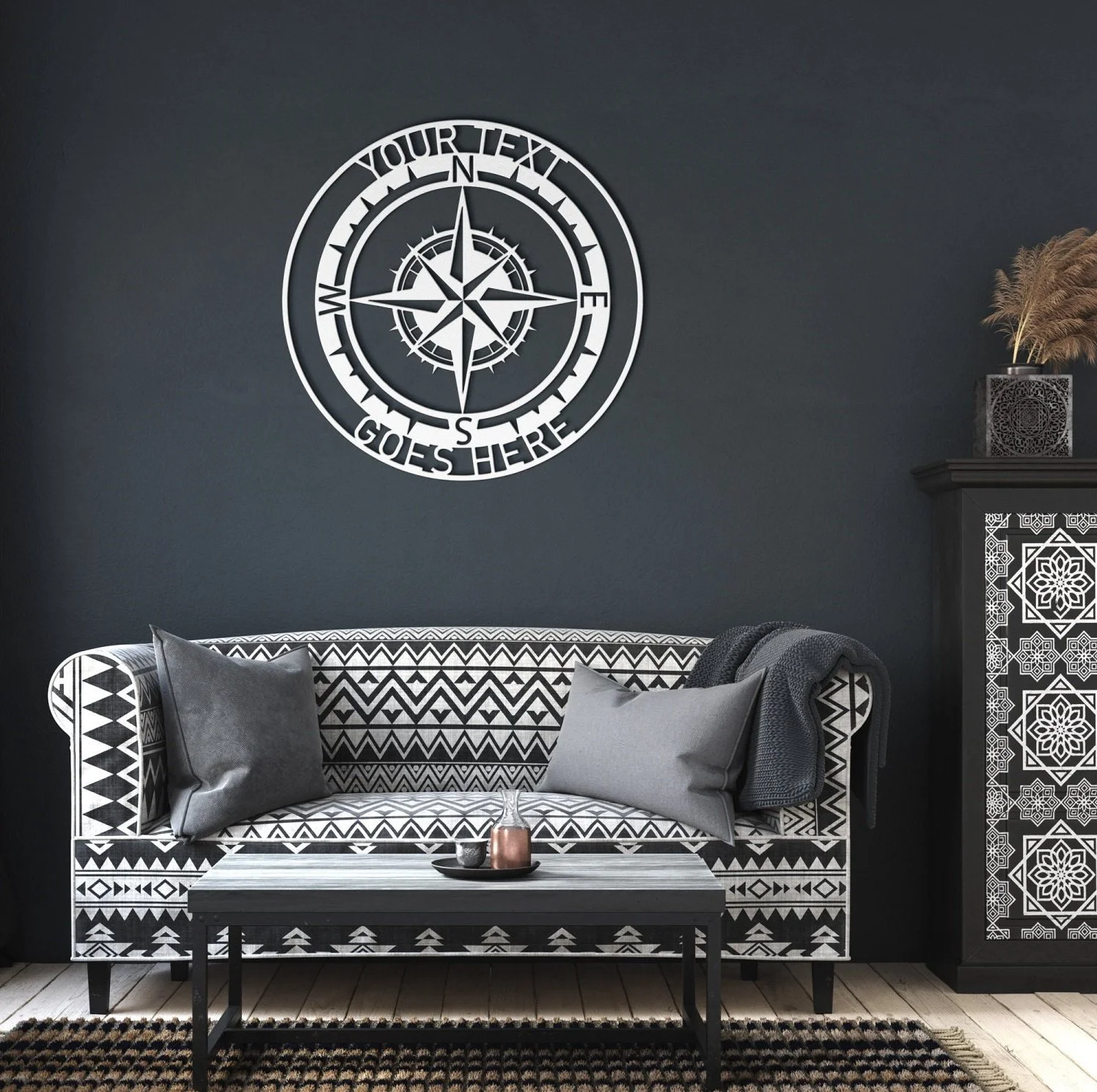 Living room with black wall, tribal-patterned black and white sofa, gray pillows, black and white coffee table with small decor, dark cabinet with geometric design, and a wall decor of a compass rose with text that reads 'Your Text Goes Here'.