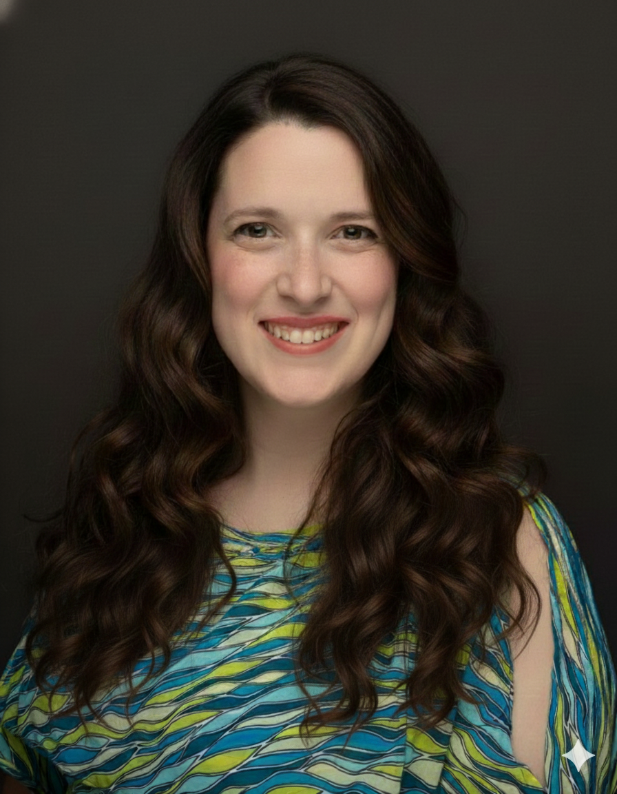 Portrait of a woman with long, wavy brown hair, smiling, wearing a colorful patterned top, against a dark background.