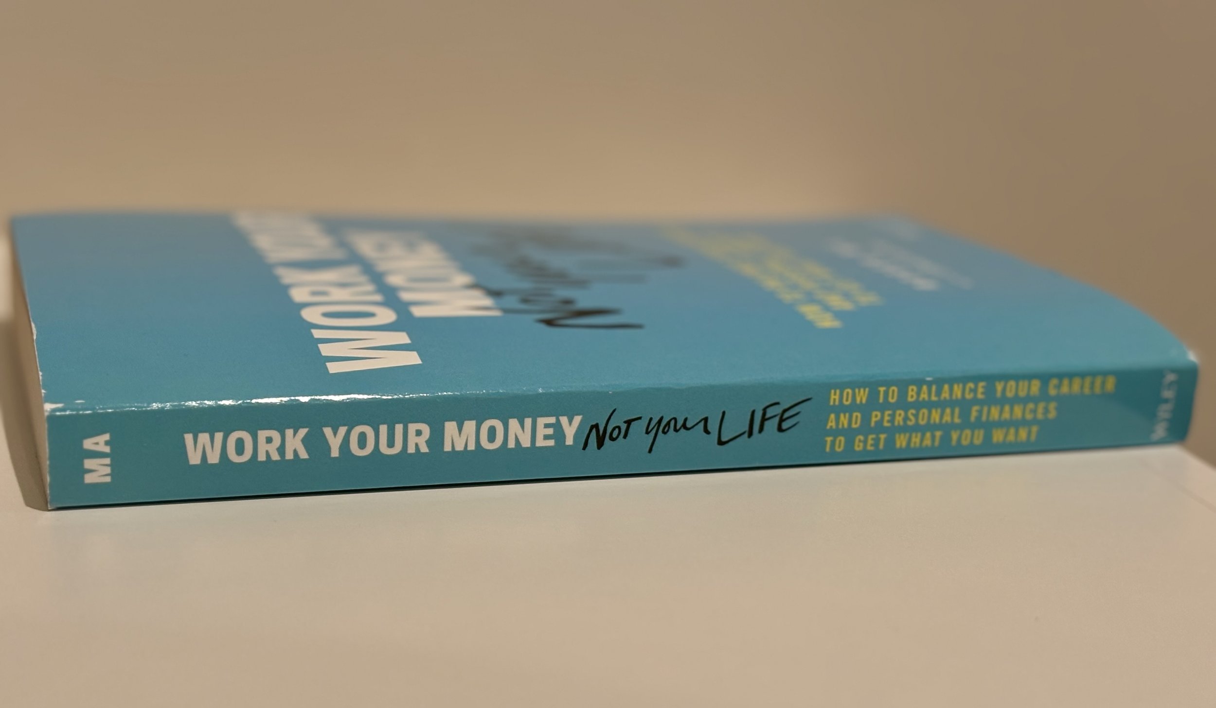Book titled 'Work Your Money Not Your Life' with subtitle 'How to balance your career and personal finances to get what you want', lying on a flat surface.