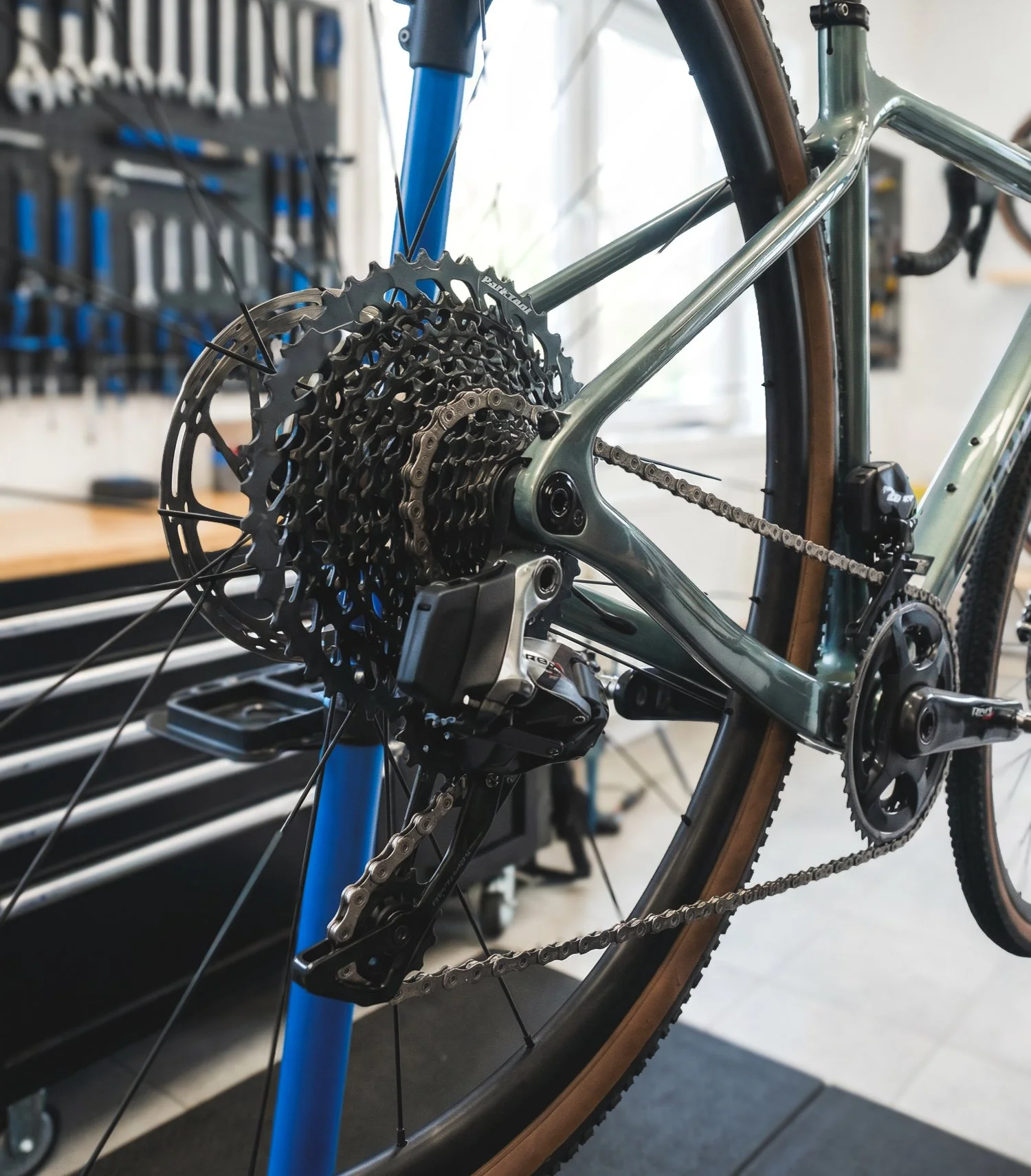 Close-up of a mountain bike's rear derailleur and gear cassette in a bike workshop.
