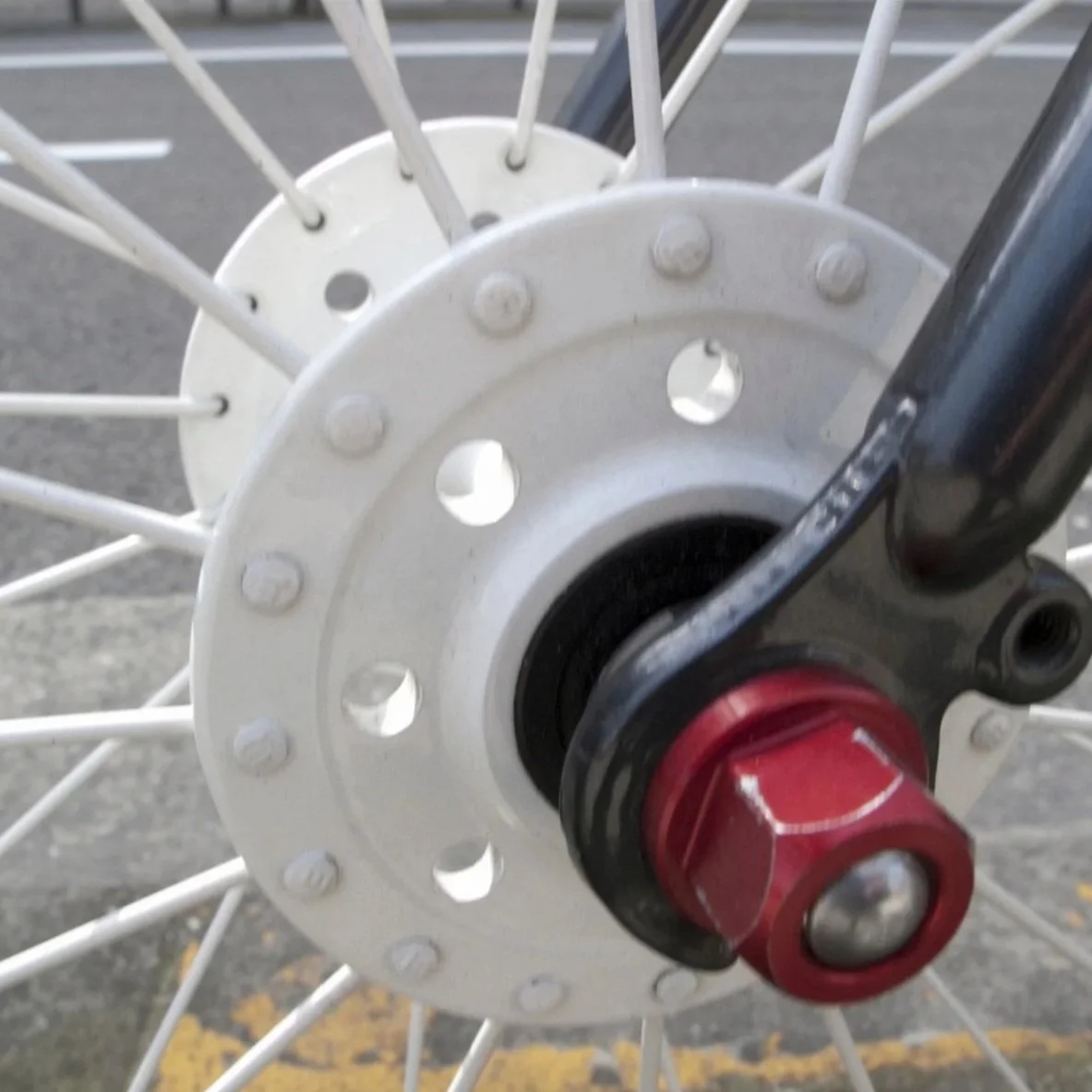 Close-up of a motorcycle wheel hub and spokes, with a wheel axle and black suspension fork.