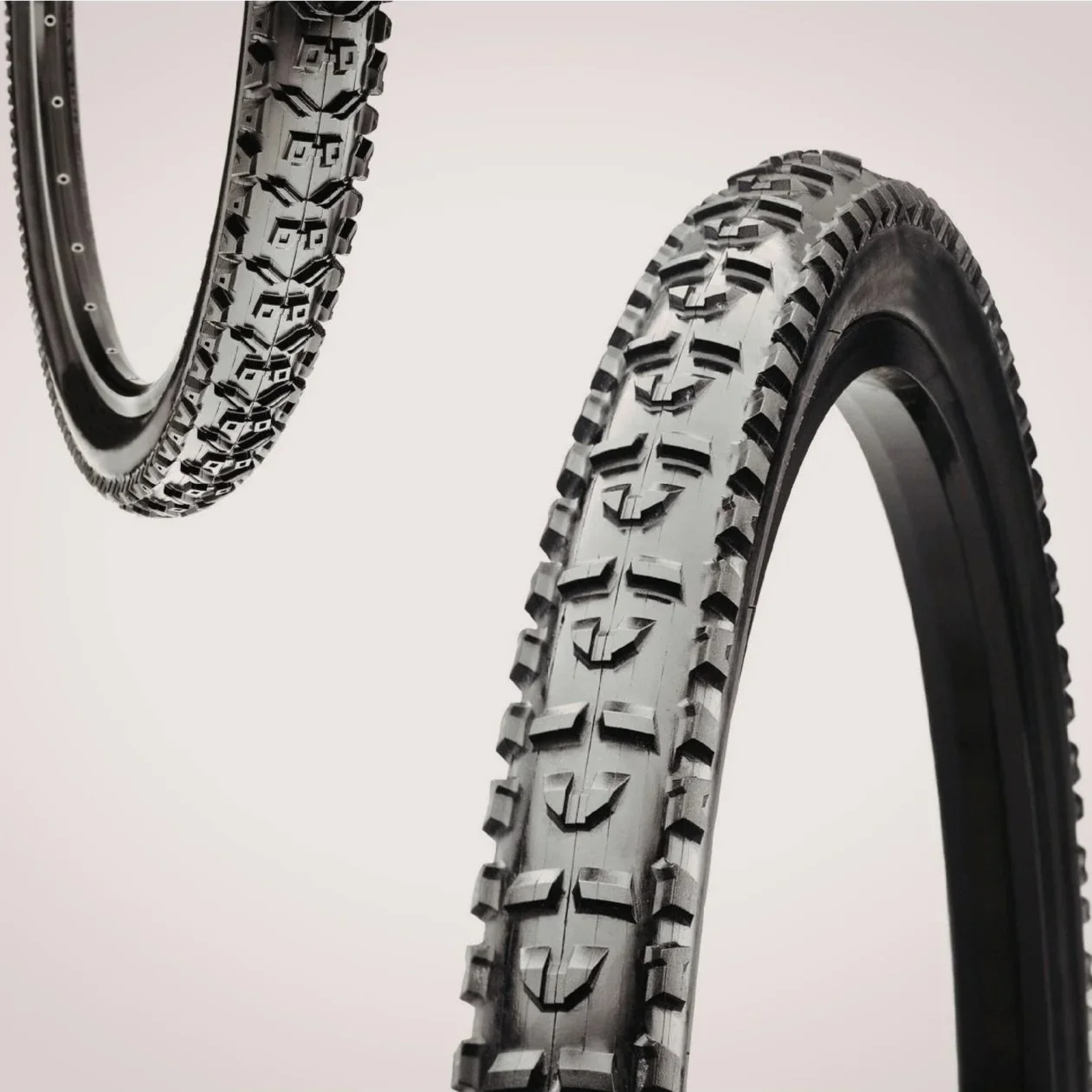 Two black mountain bike tires with detailed tread patterns against a plain white background.